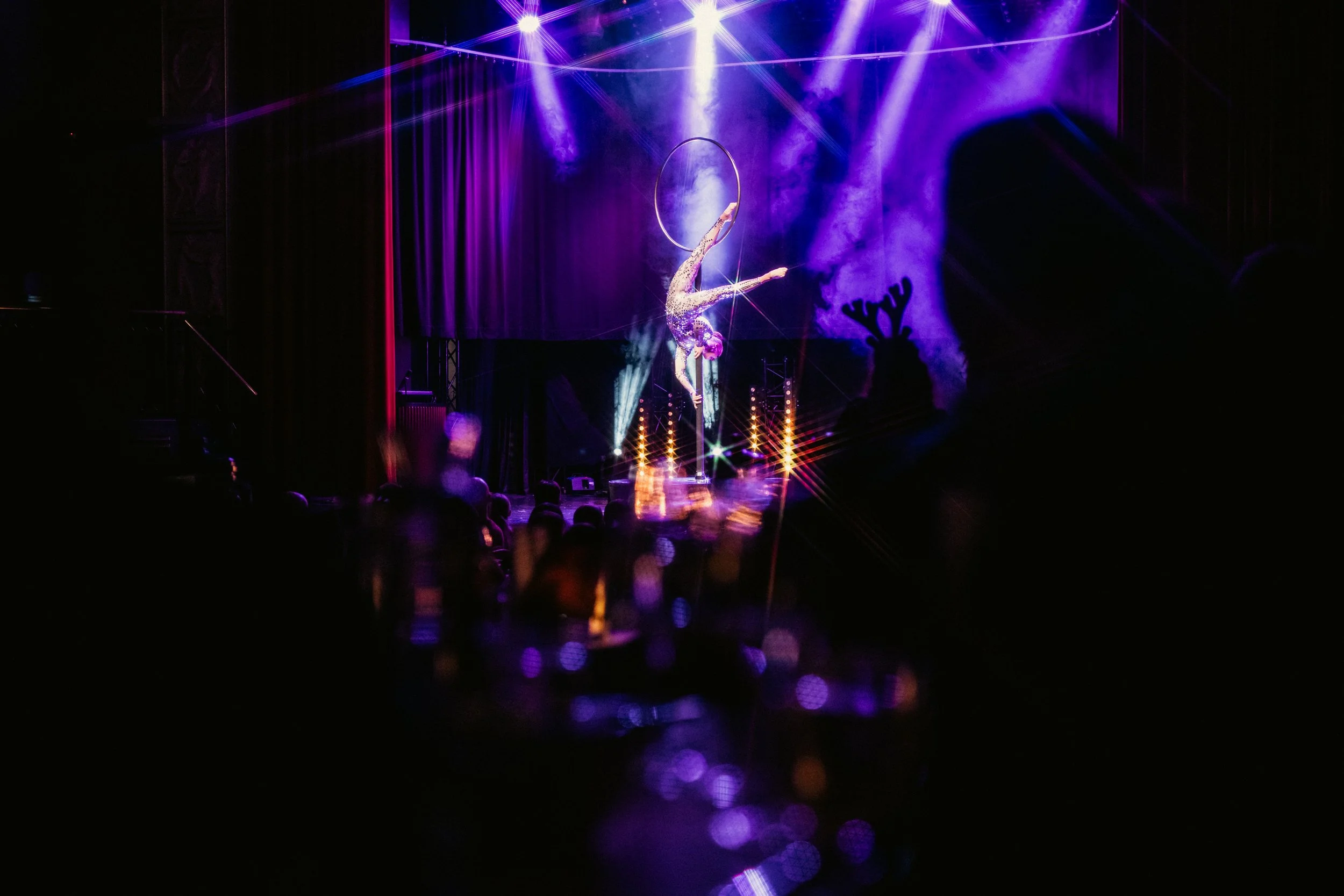 Sirkustanssitaiteilija esittää akrobaattista esitystä hennon valokeilan ja lavasteiden keskellä