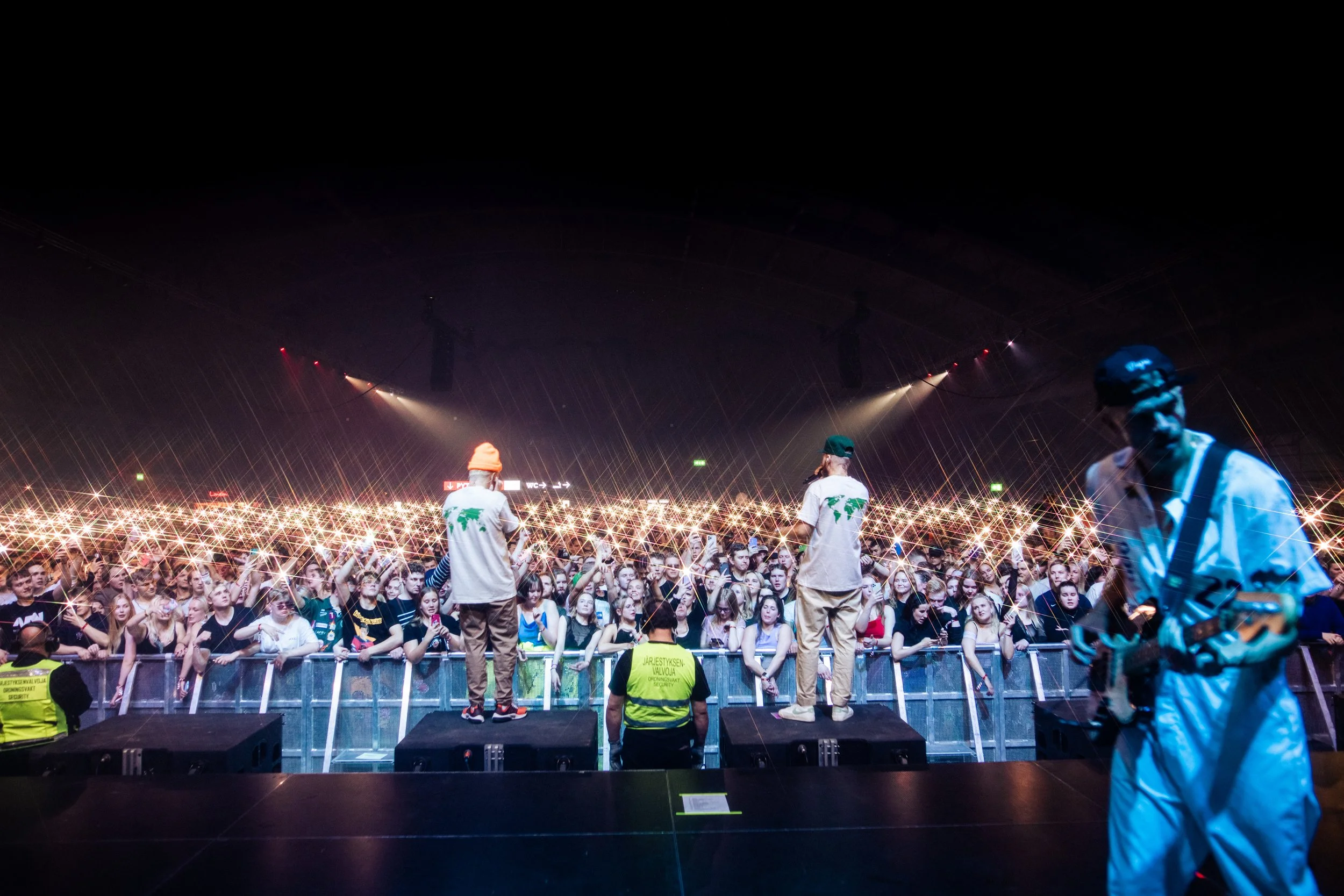 Livekonsertti, suuri yleisö ja muusikot lavalla.