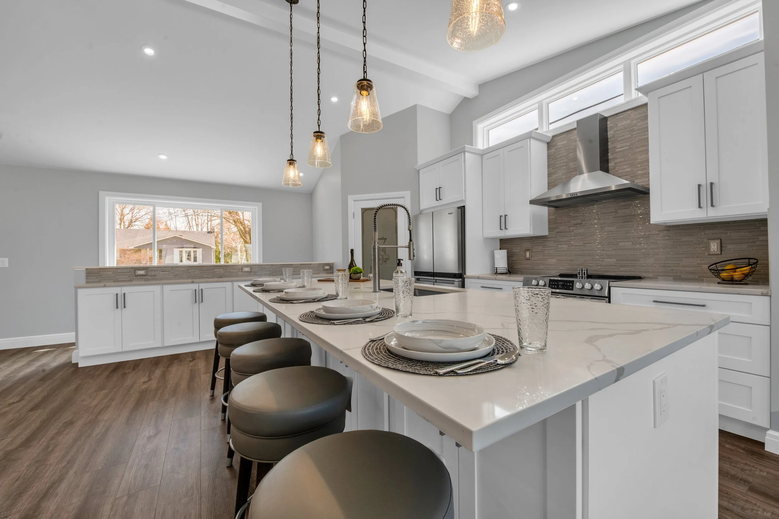 Modern kitchen with white cabinets, marble island, pendant lighting, and stainless steel appliances.