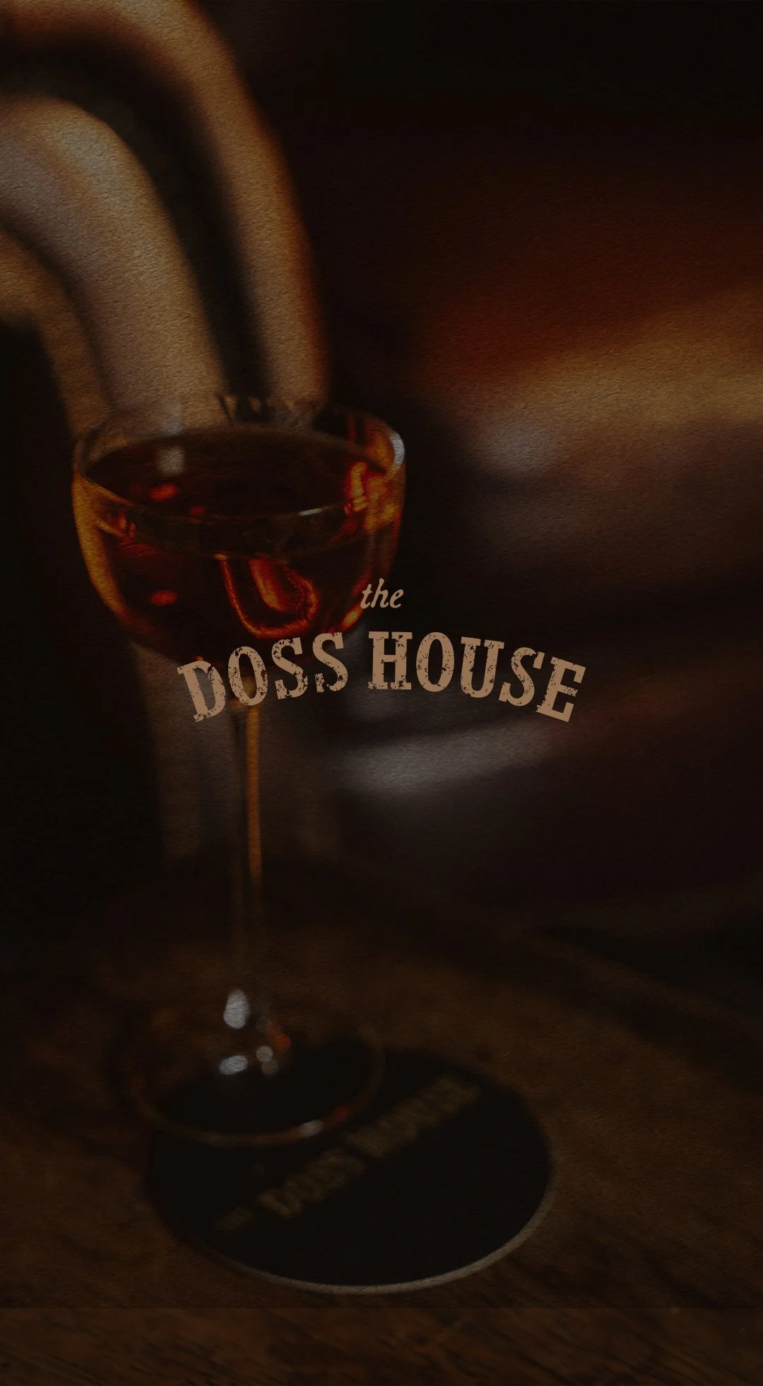 A glass of red wine on a coaster with the words 'the Doss House' written across the image.