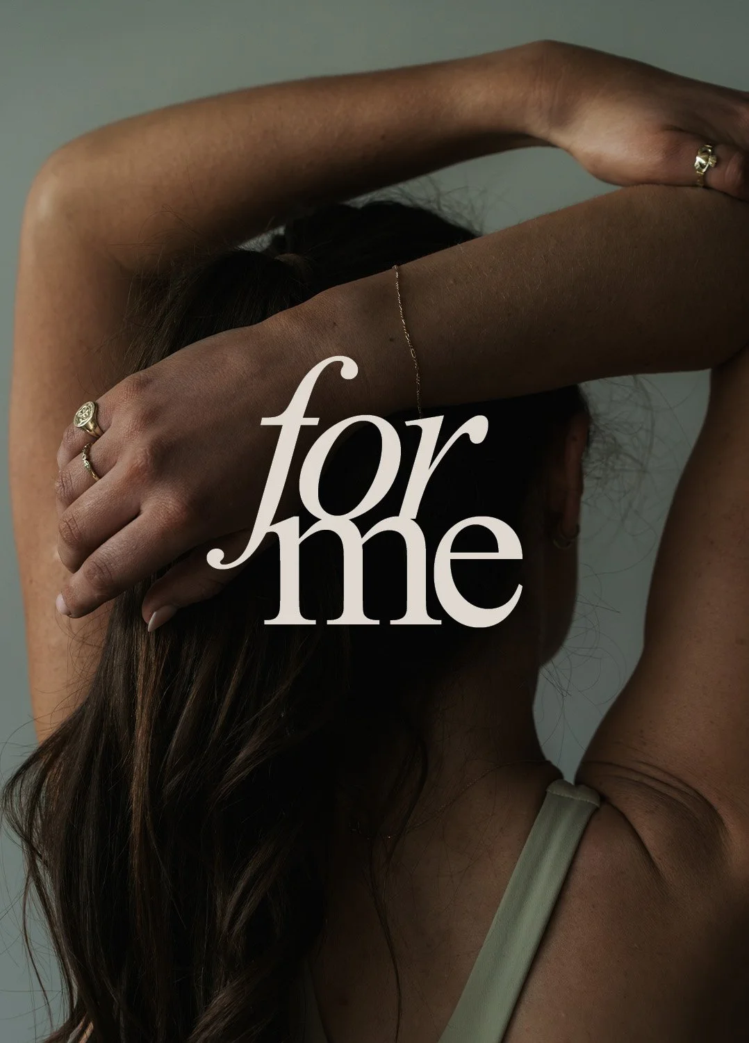 A woman with dark hair covering her face, her arm raised behind her head, showing jewelry, with the words 'for me' overlayed on the image.