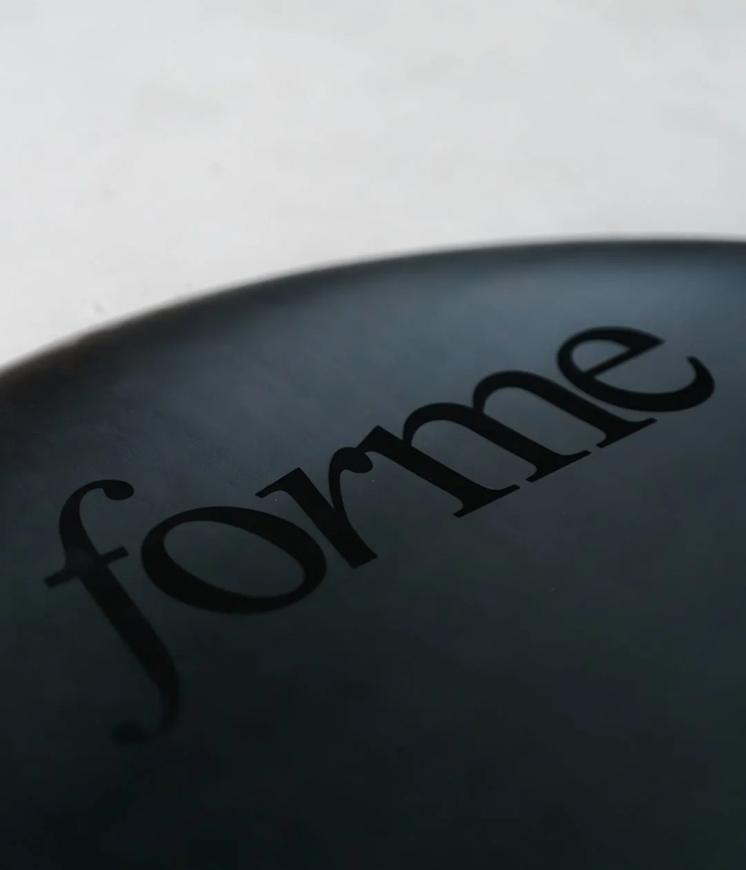 Close-up of a black round object with the word 'for me' written on it in black lowercase letters.