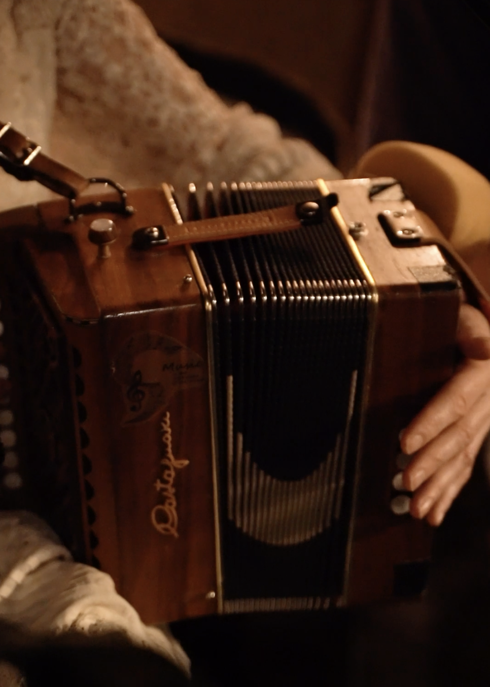 An accordion being played by a person, showing hands and part of the instrument's body