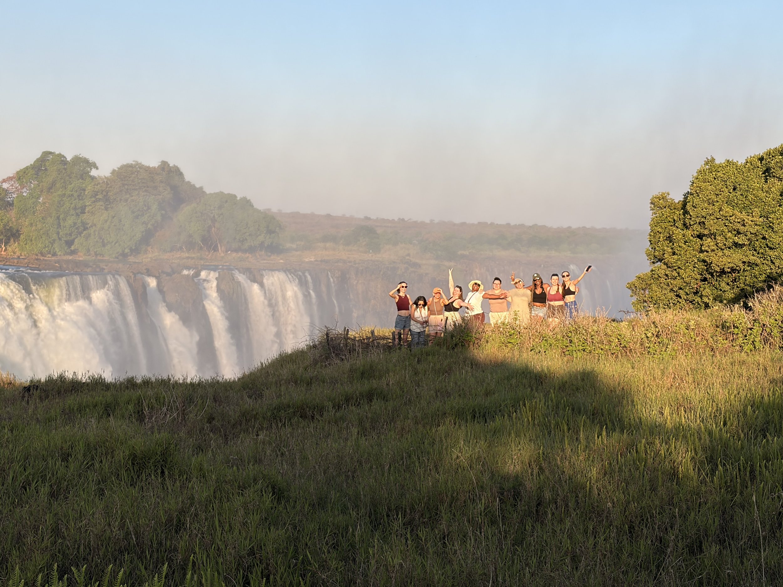 women at Victoria falls dancing and laughing