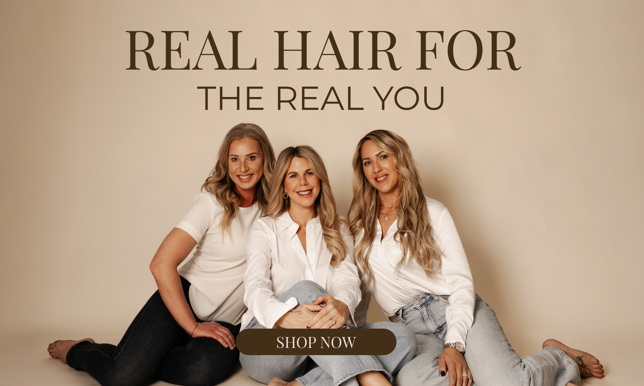 Three women sitting on the floor smiling, with a beige background and large text that reads "Real Hair for The Real You." A brown button below says "Shop Now."