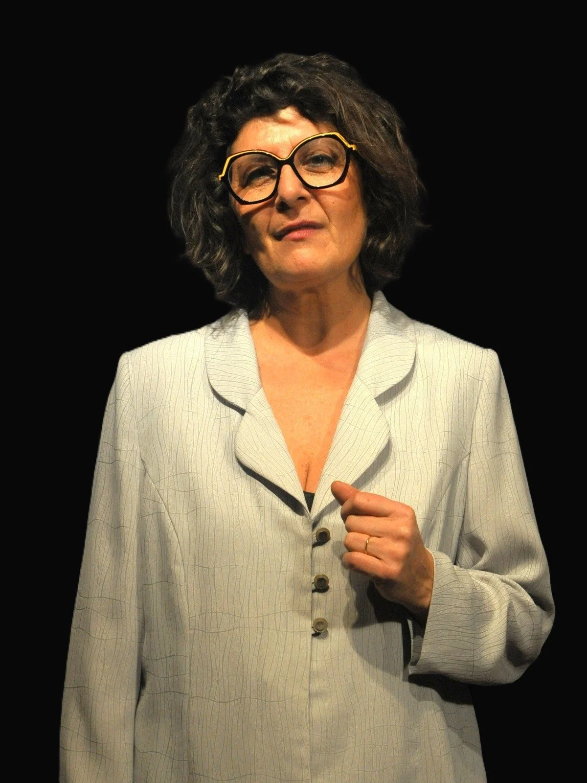 Ritratto di laura Pasi per il team building aziendale, in giacca grigia e occhiali a vista moderni, posa formale su fondo scuro