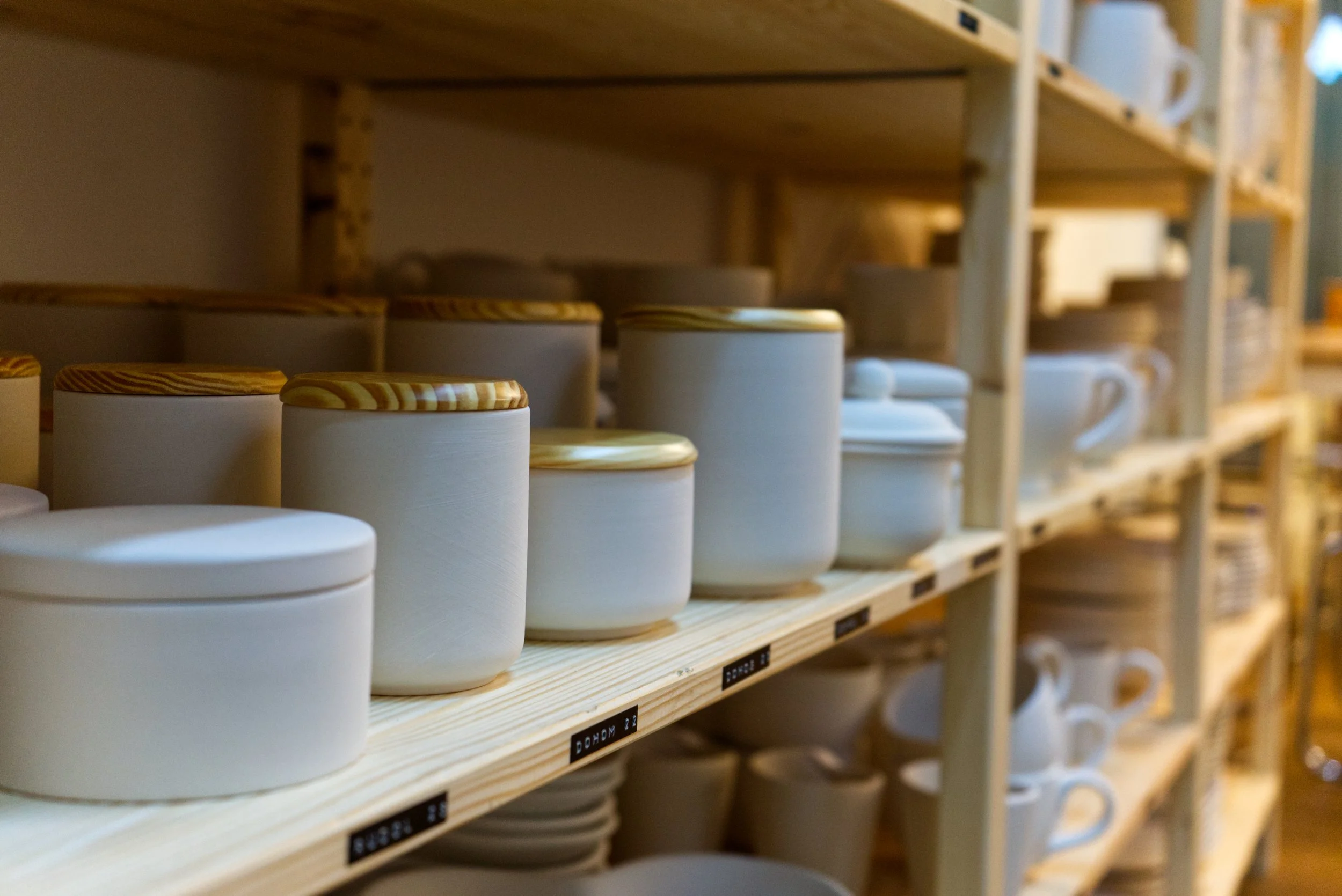 Regale mit weißen Keramikbehältern und Tassen in einem Geschäft oder Lager.
