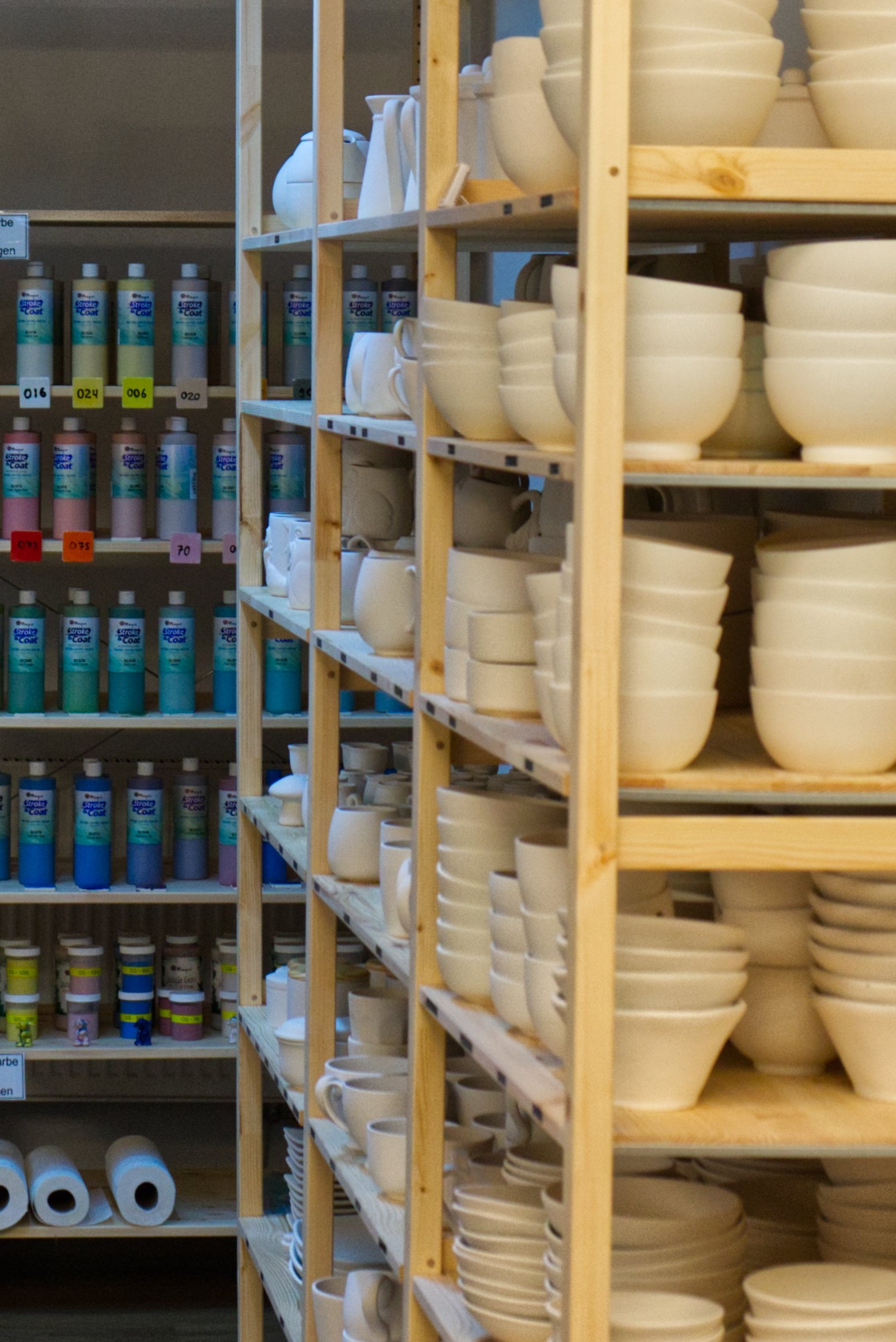 Holzregale mit weißen Geschirr, Tassen und Schalen, in einem Lagerraum