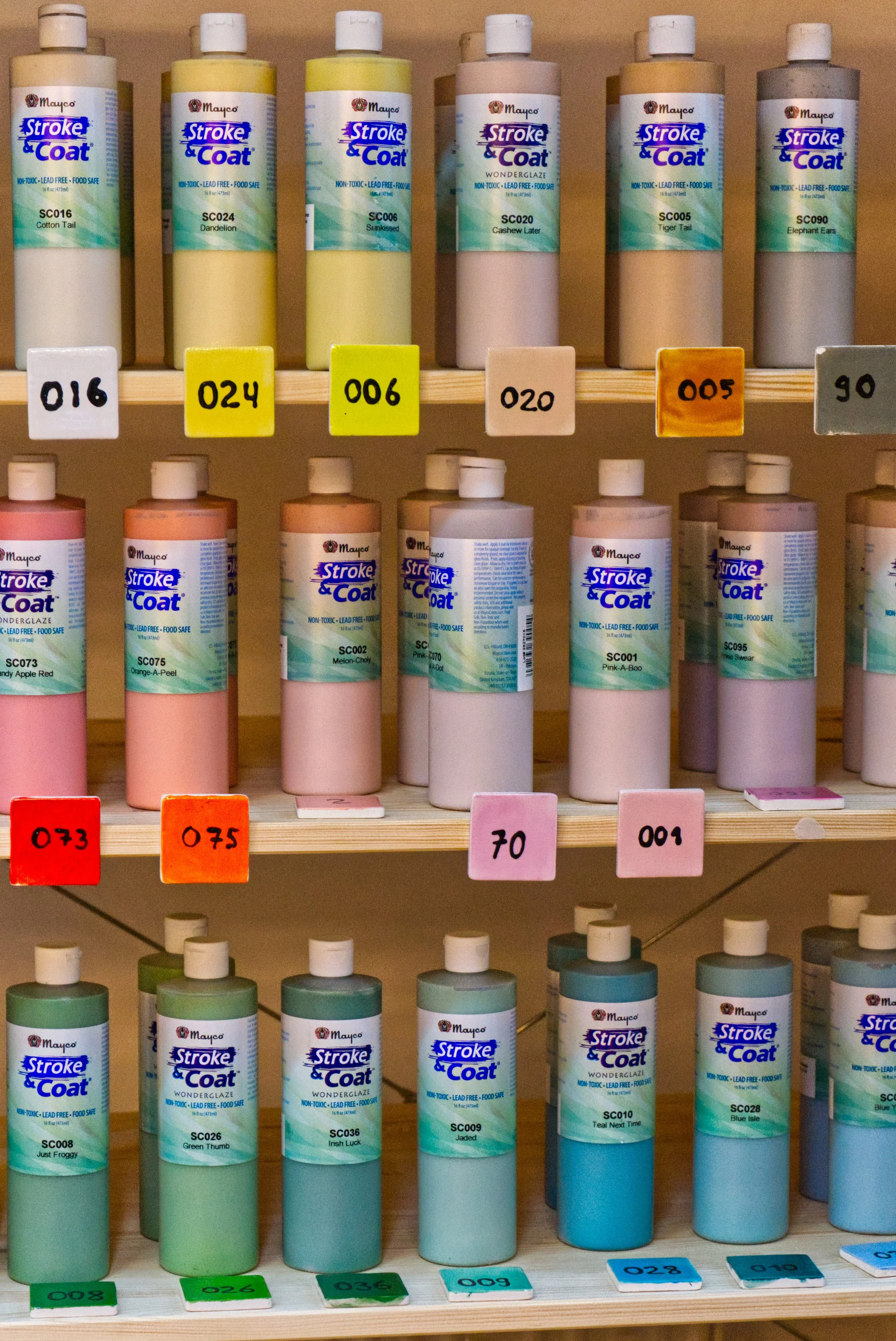 Regale mit Farbfedern in Flaschen, sortiert nach Farben mit Labels und Farbcodes.