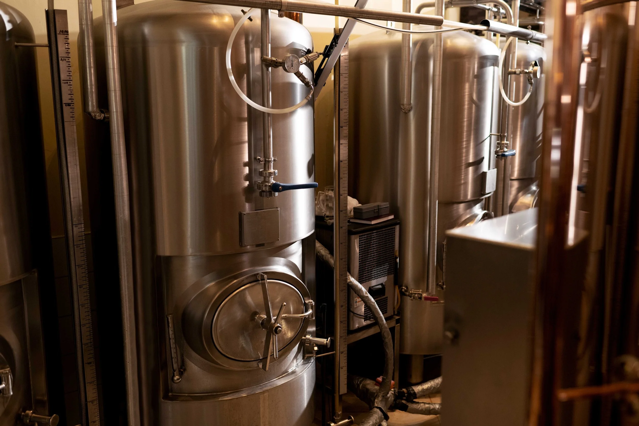 Industrial stainless steel tanks and machinery in a brewery or distillery setting.