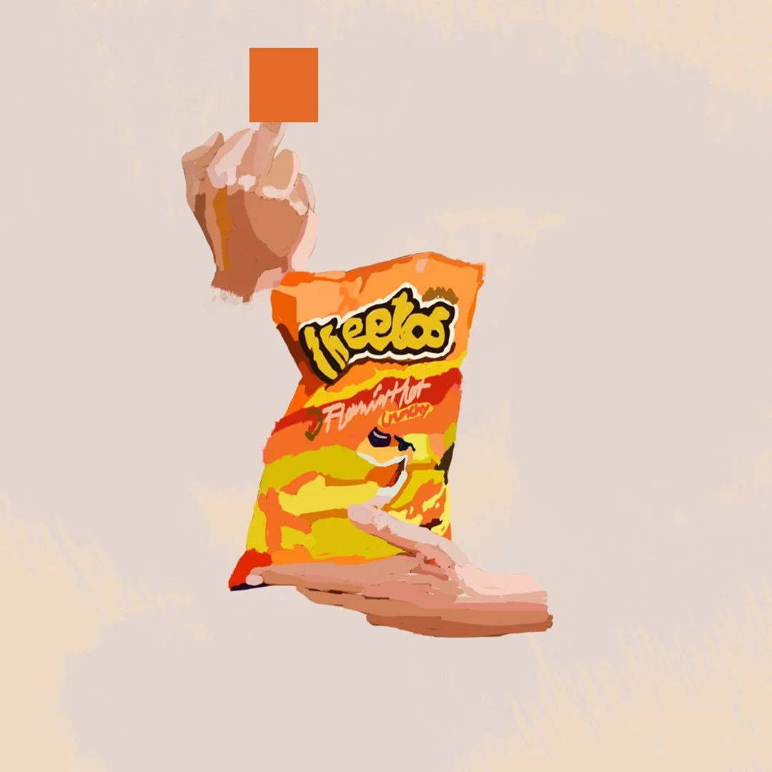 A hand holding a small orange square above a bag of Lay's Flamin' Hot Cheetos.