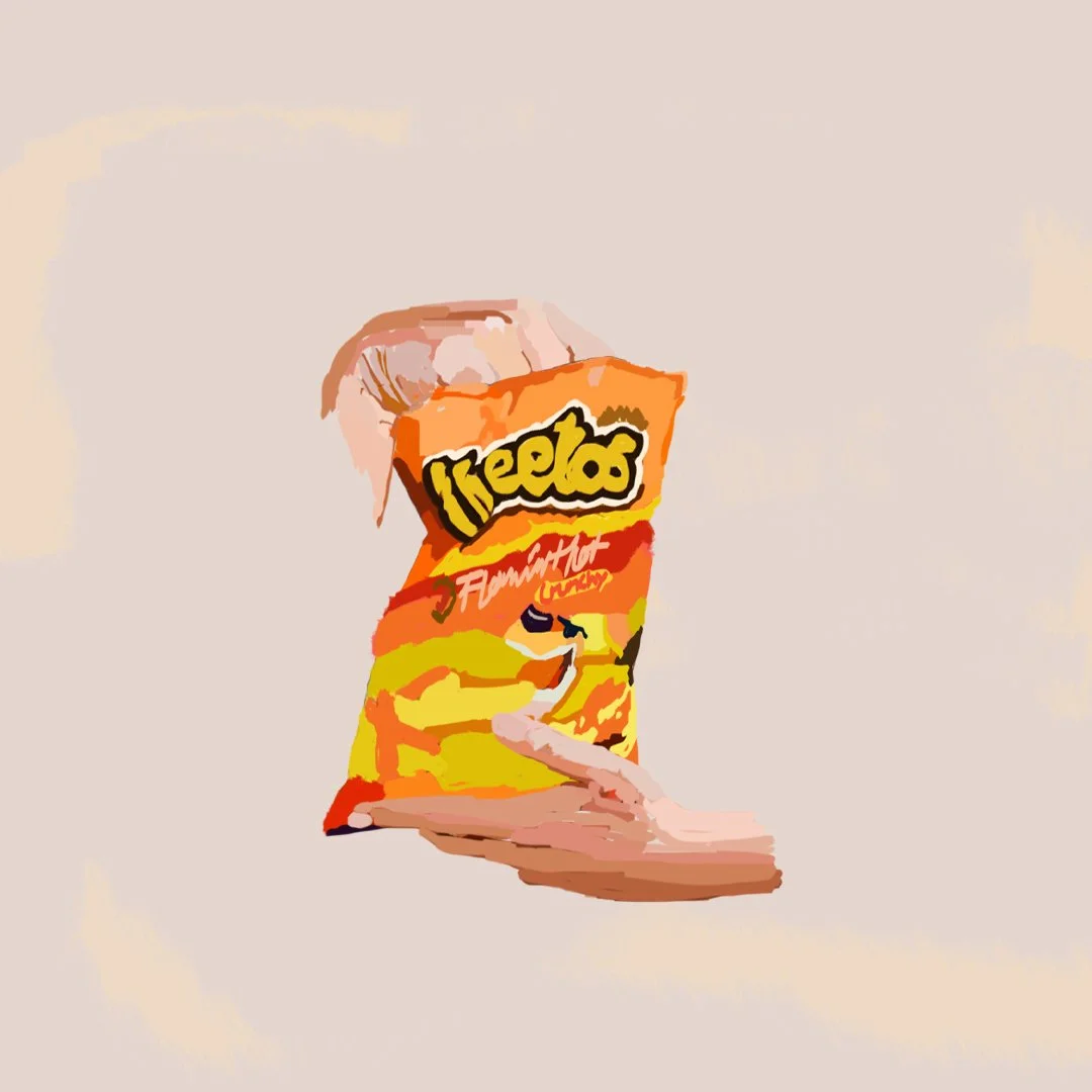 A person's hand holding a bag of flaming hot cheetos snack.