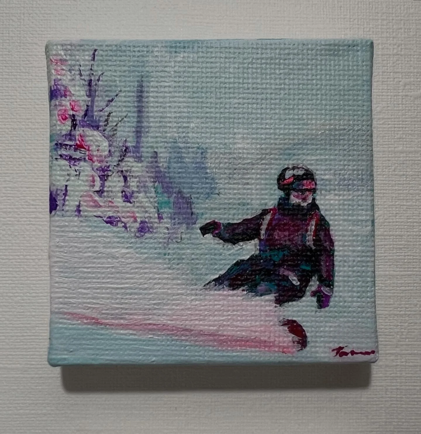 A small painting of a skier in a black and red outfit with a helmet and goggles, sitting on snow next to pink and purple flowers on the left side, with a light blue background.