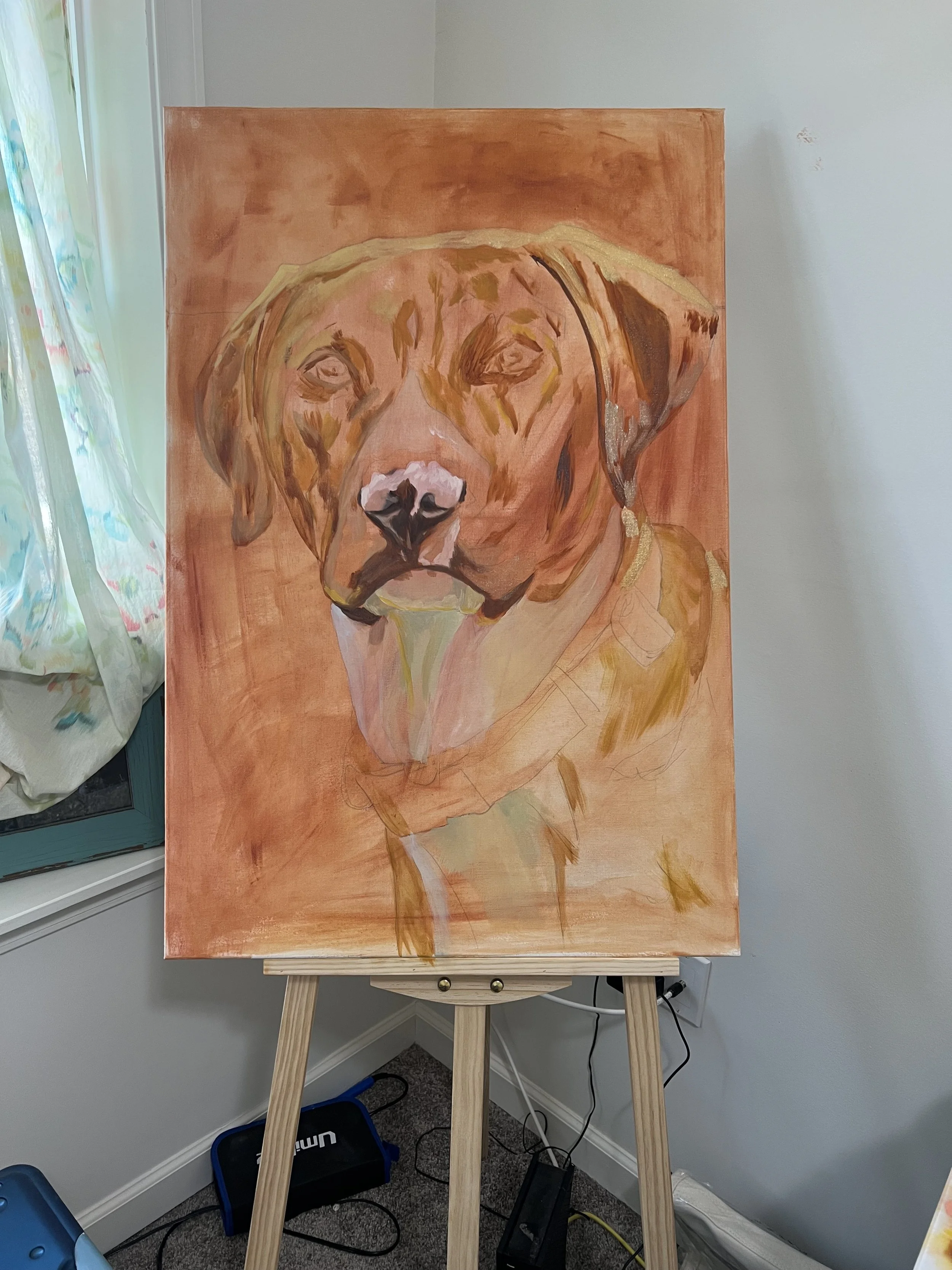 A painting of a dog, specifically a brown dog with a white spot on its nose, on a wooden easel in a room with a window and a white wall.