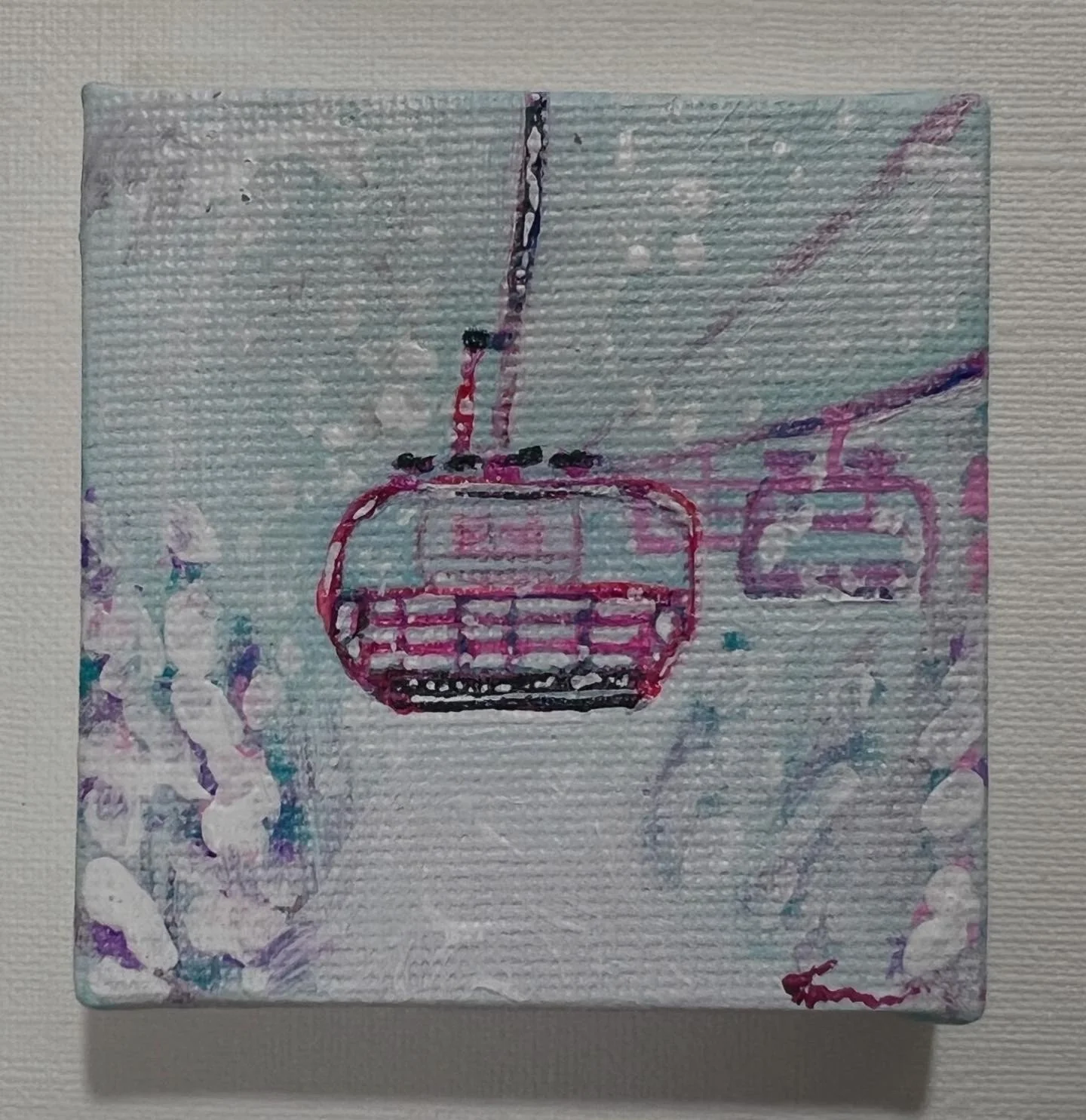 Painted canvas depicting a cable car or gondola with a pink and purple outline, hanging from a cable, with a blurry background of sky and snow.