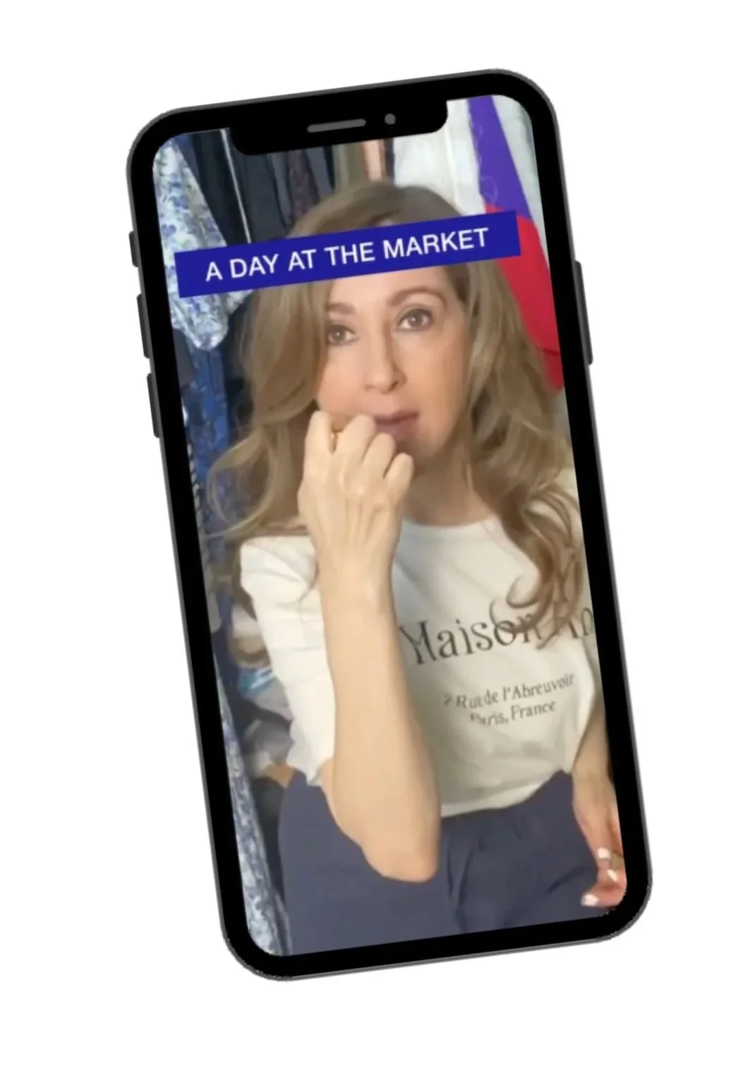Sonia Sache with long wavy hair taking a selfie in a mirror, with a note that says "A DAY AT THE MARKET" at the top of the phone screen.