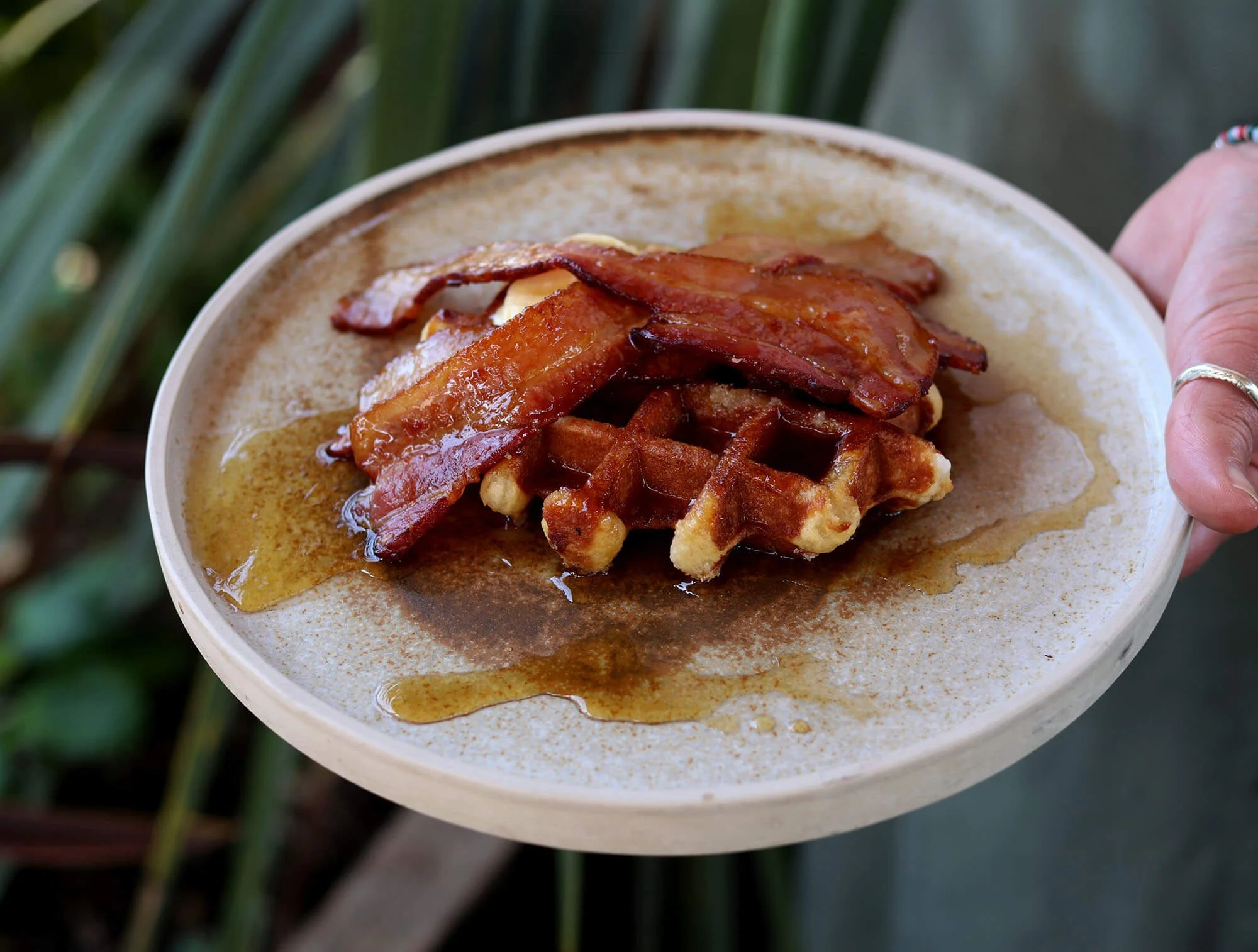 A plate of waffles and bacon with syrup