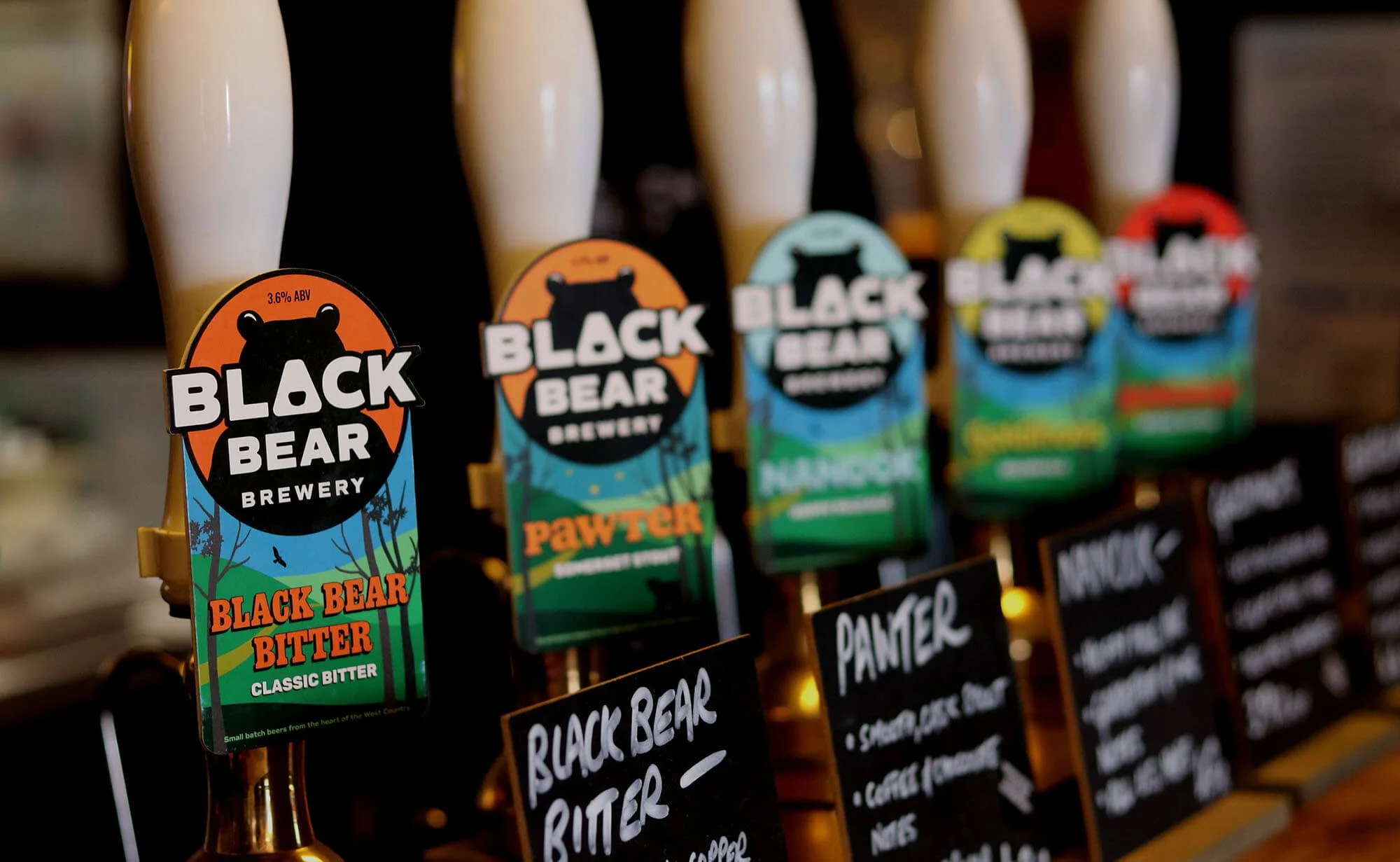 Bottles of beer from Black Bear Brewery with colorful labels featuring a bear logo, arranged in a row on a display shelf.