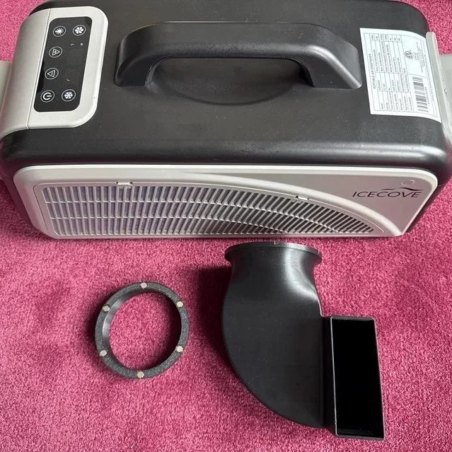Portable space heater with digital controls, a circular mounting bracket, and a black vent attachment on a pink carpet.