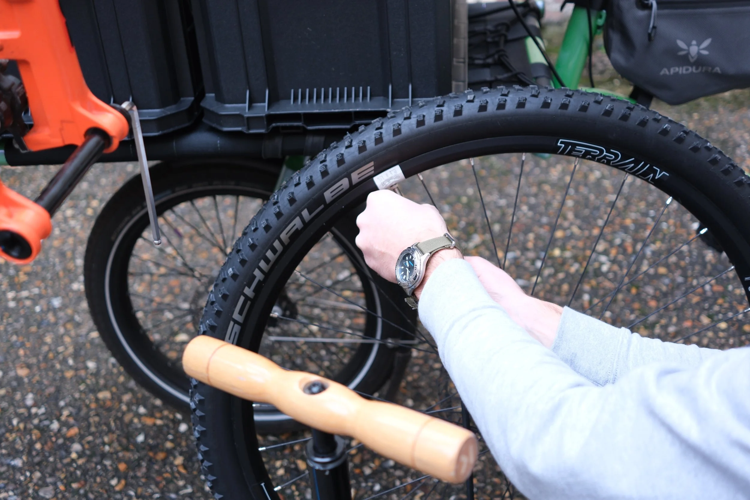 Une personne change la chambre à air d'un vélo électrique noir avec des pneus Schwalbe.