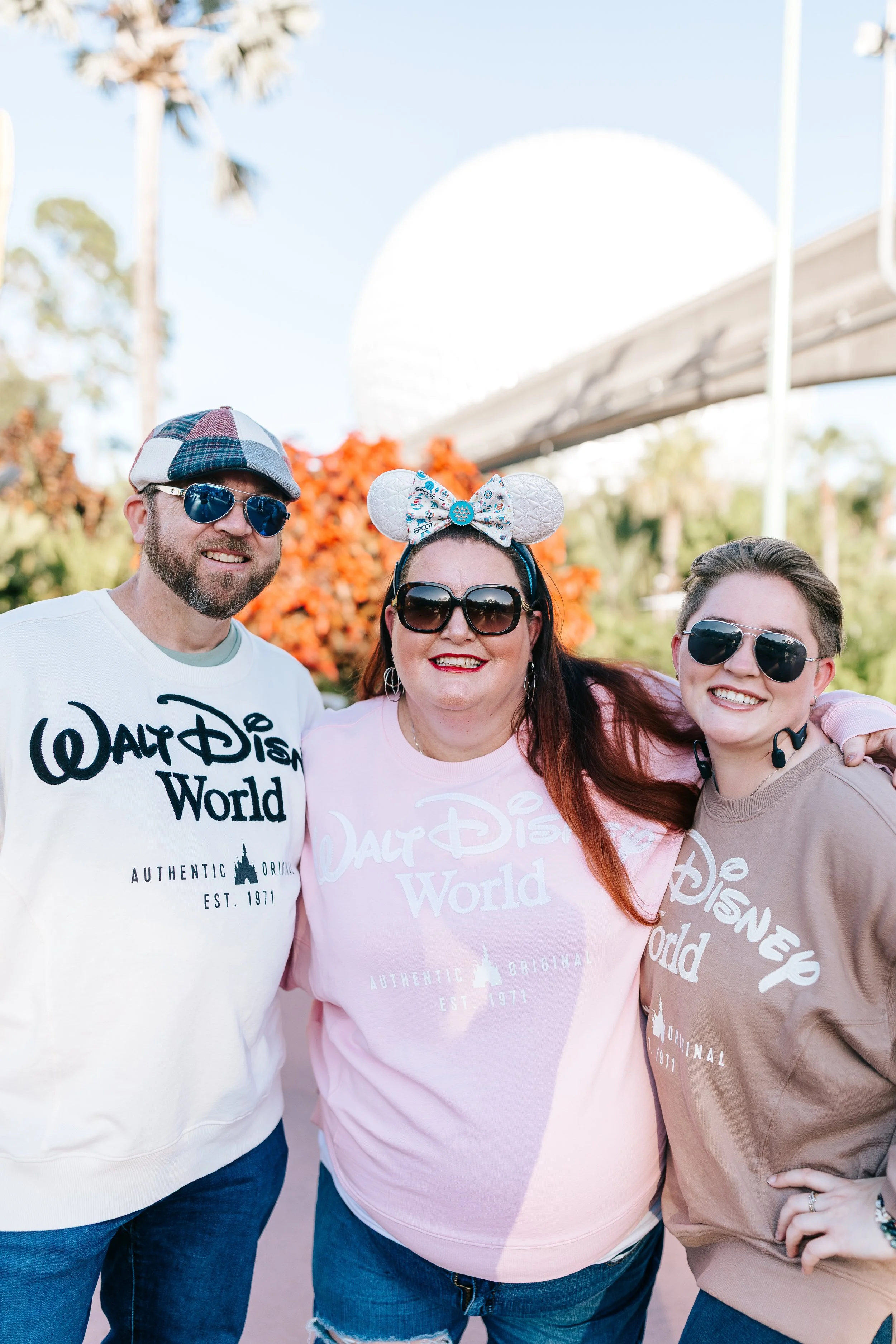 Beach scene with surfboards leaning against a palm tree, sand, ocean, and a sign for watersports.