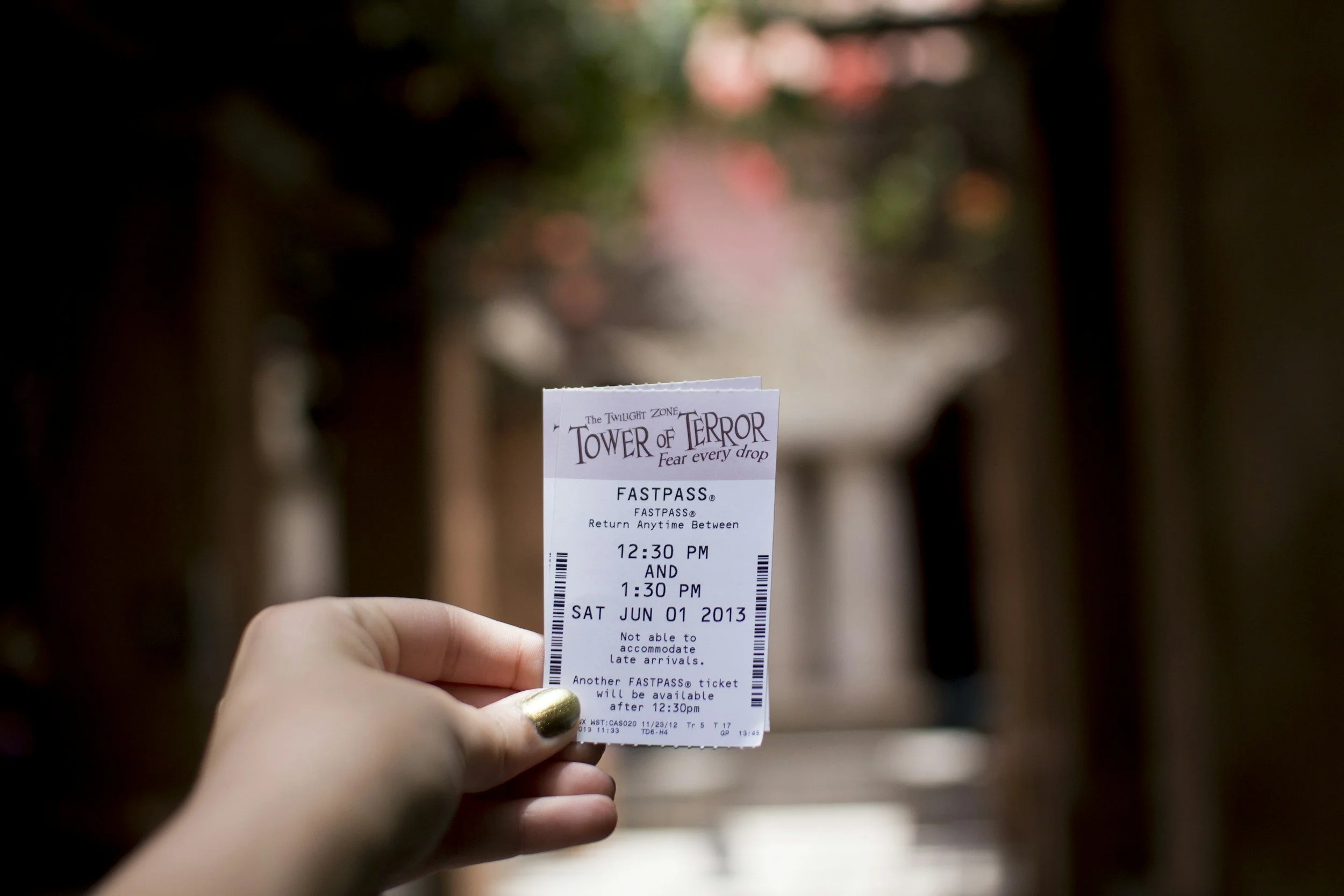 Person lying on a bed with white sheets, looking out a large window at a scenic view of the sea and distant cityscape during daylight.