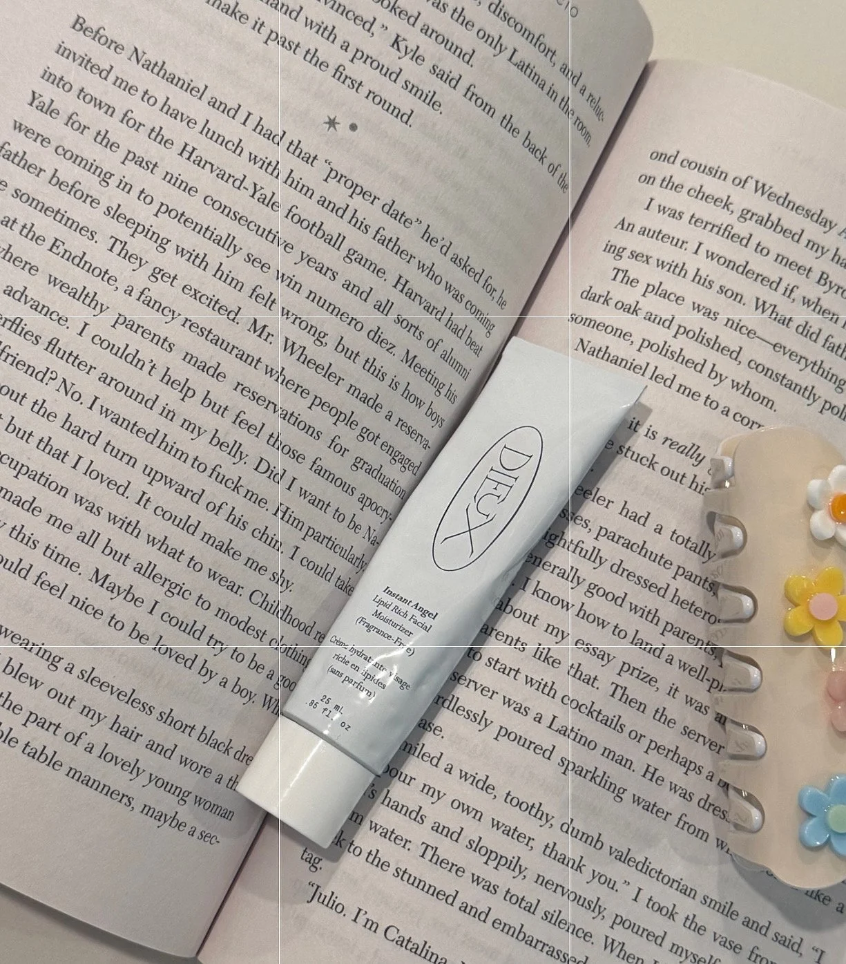 An open book, a tube of DiorD Liquid X lipstick, a flower-shaped hair clip, and a small flower hair accessory on a page of a book.
