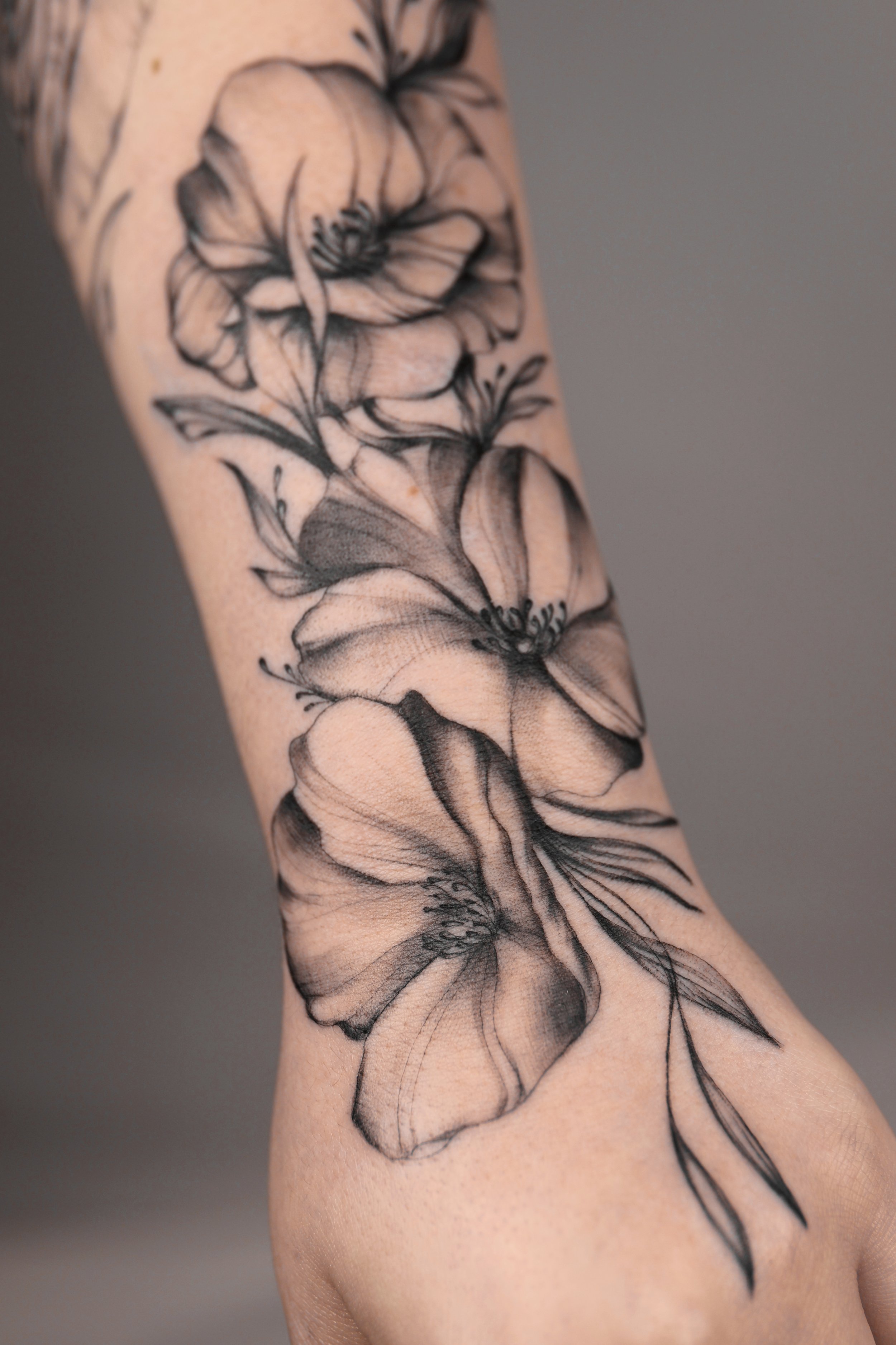 Tatouage en noir et blanc de fleurs délicates sur le bras.