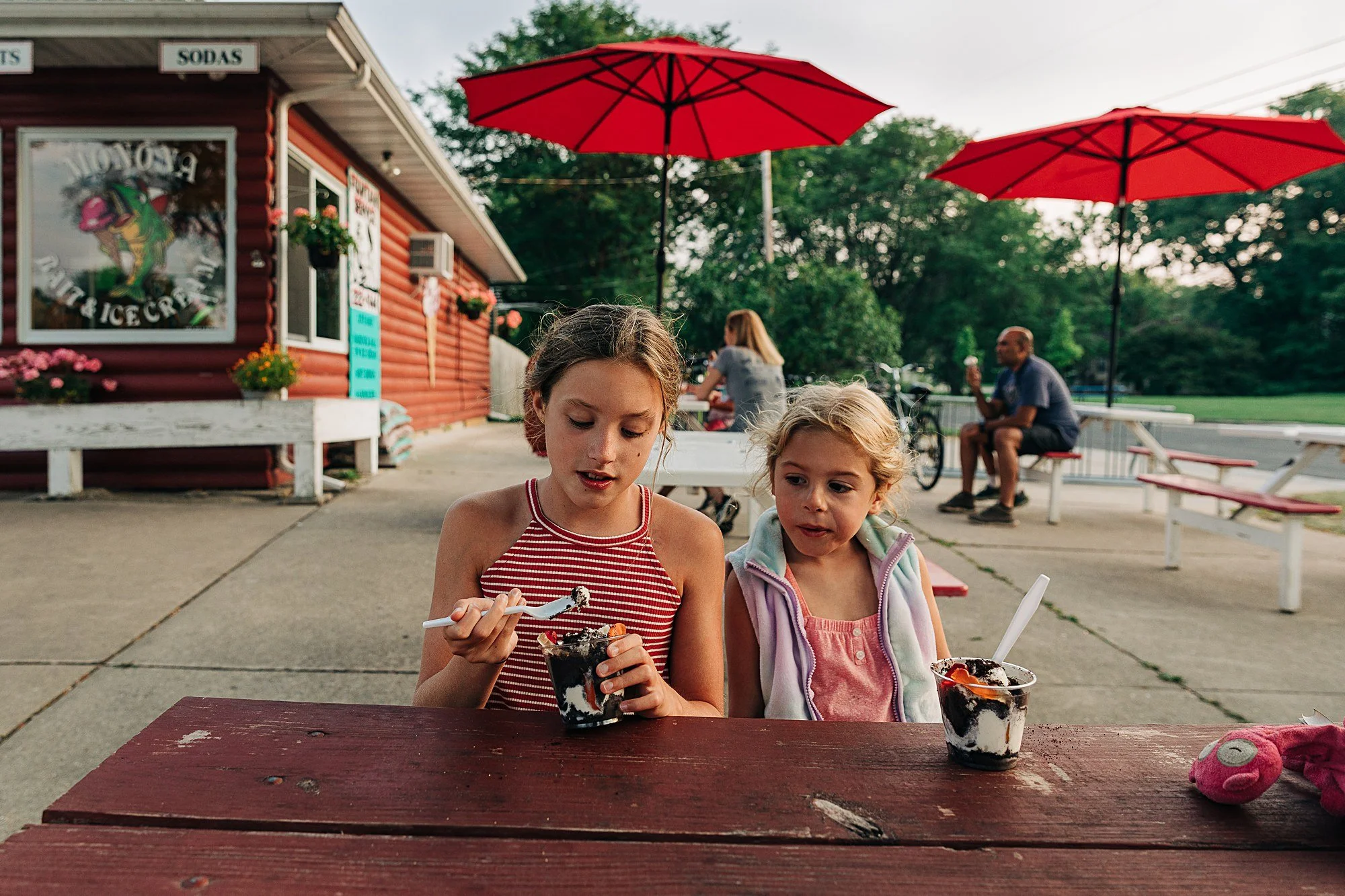 two young girls eat ice cream at ice cream parlor picnic table