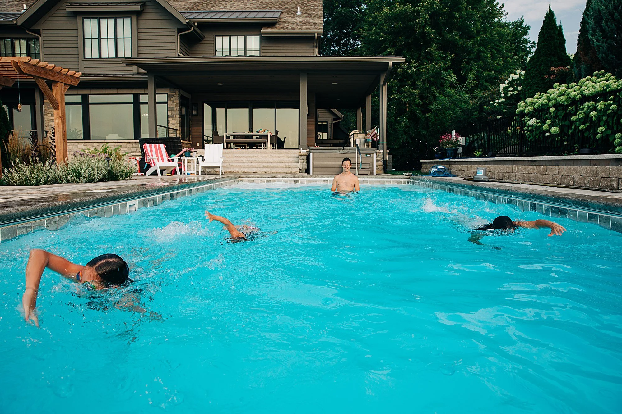Mom and 2 daughters race in swimming pool while dad watches on