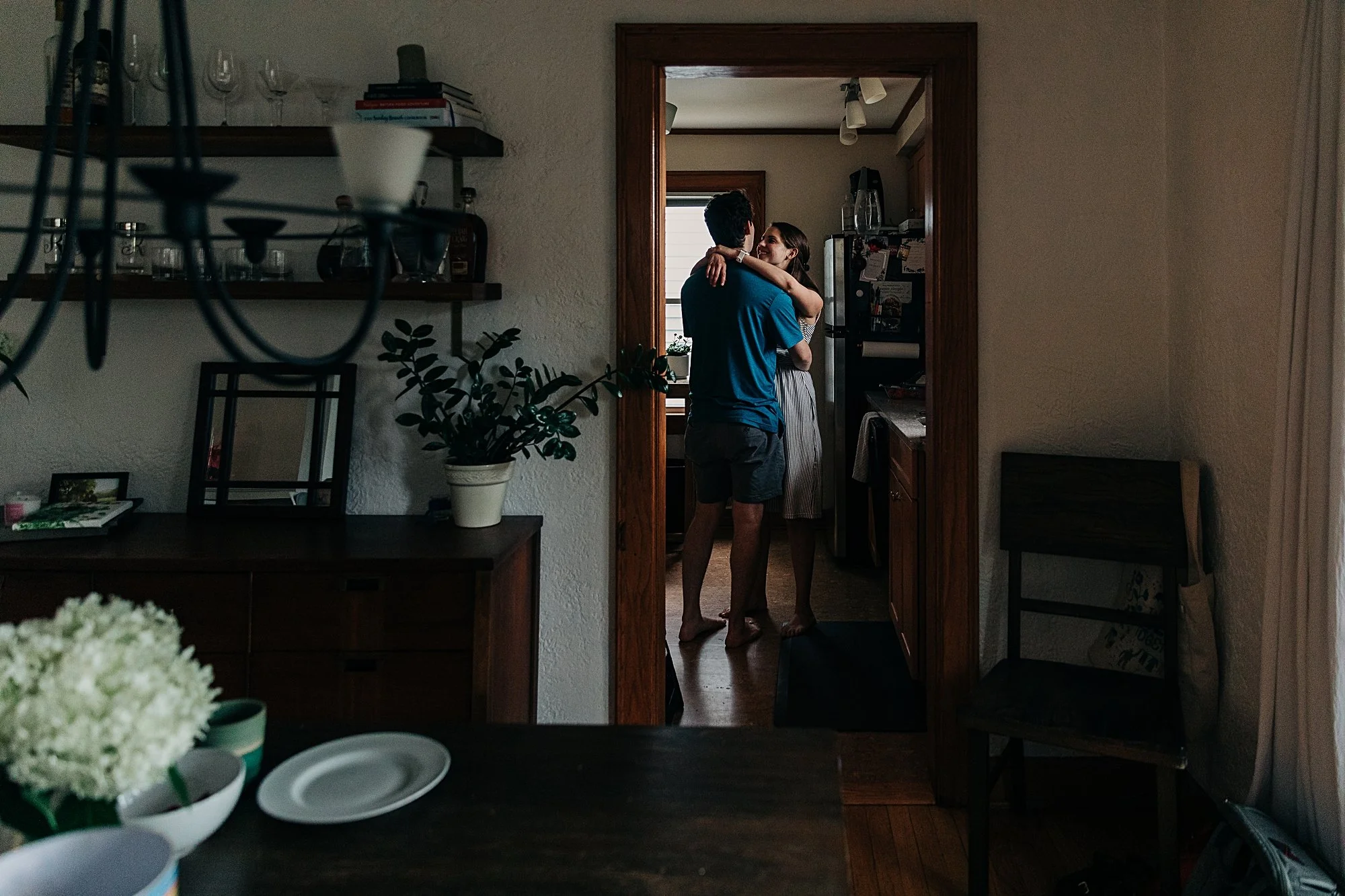 Two parents dance alone in the kitchen with soft window light