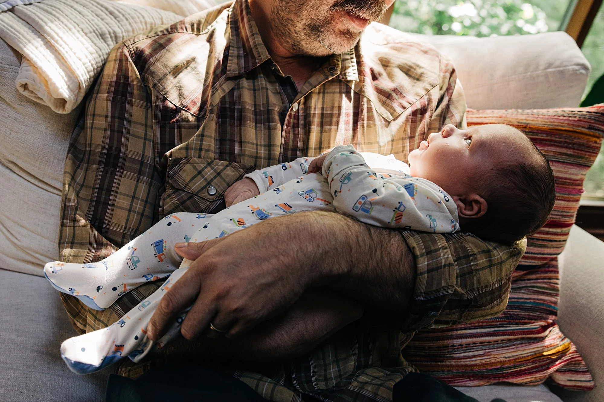 A man holding a baby and looking at each other while sitting on a couch in a cozy living room.