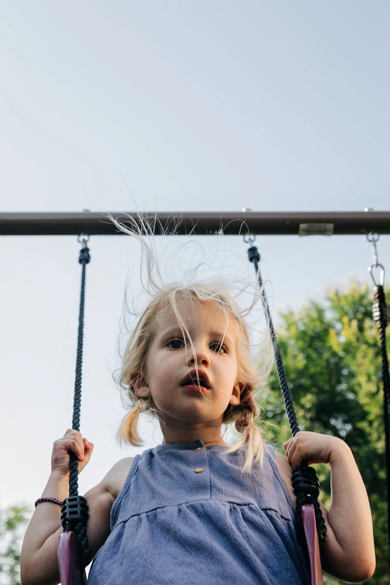 girl swings on backyard swing and hair flies up around head