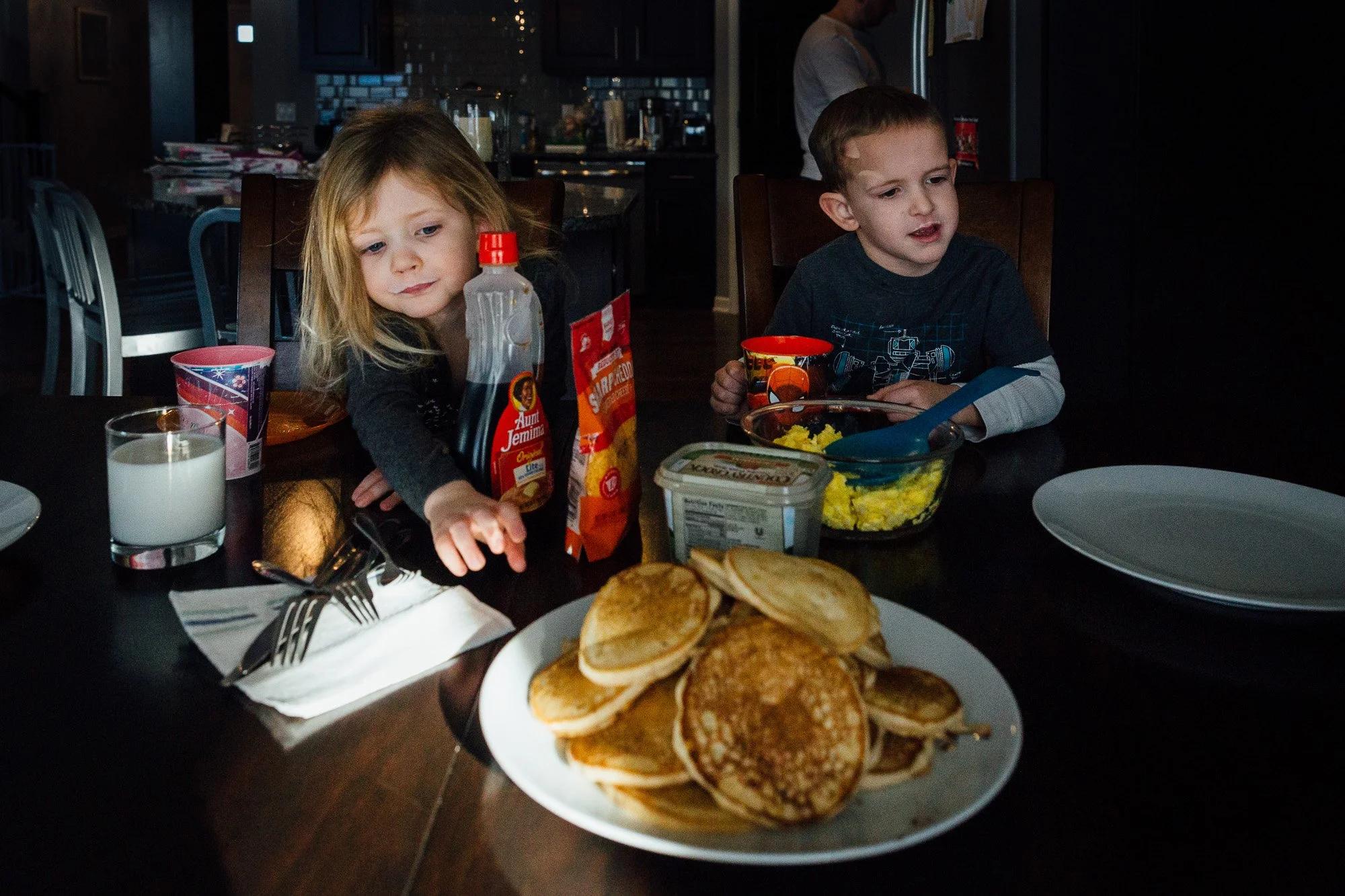 kids reach for pancakes in morning light