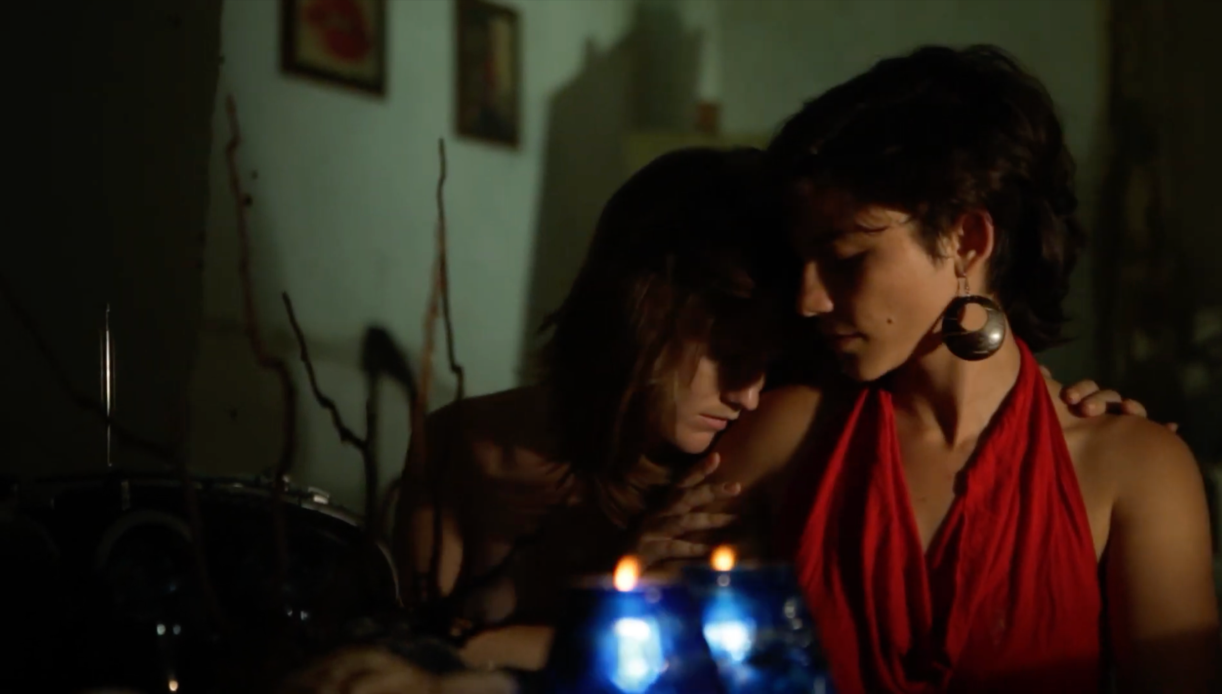 Patricia Machin Portfolio Designer Art director Miami Two women share a tender moment with their foreheads touching, sharing an intimate embrace in a dimly lit room, with candles creating a soft glow.