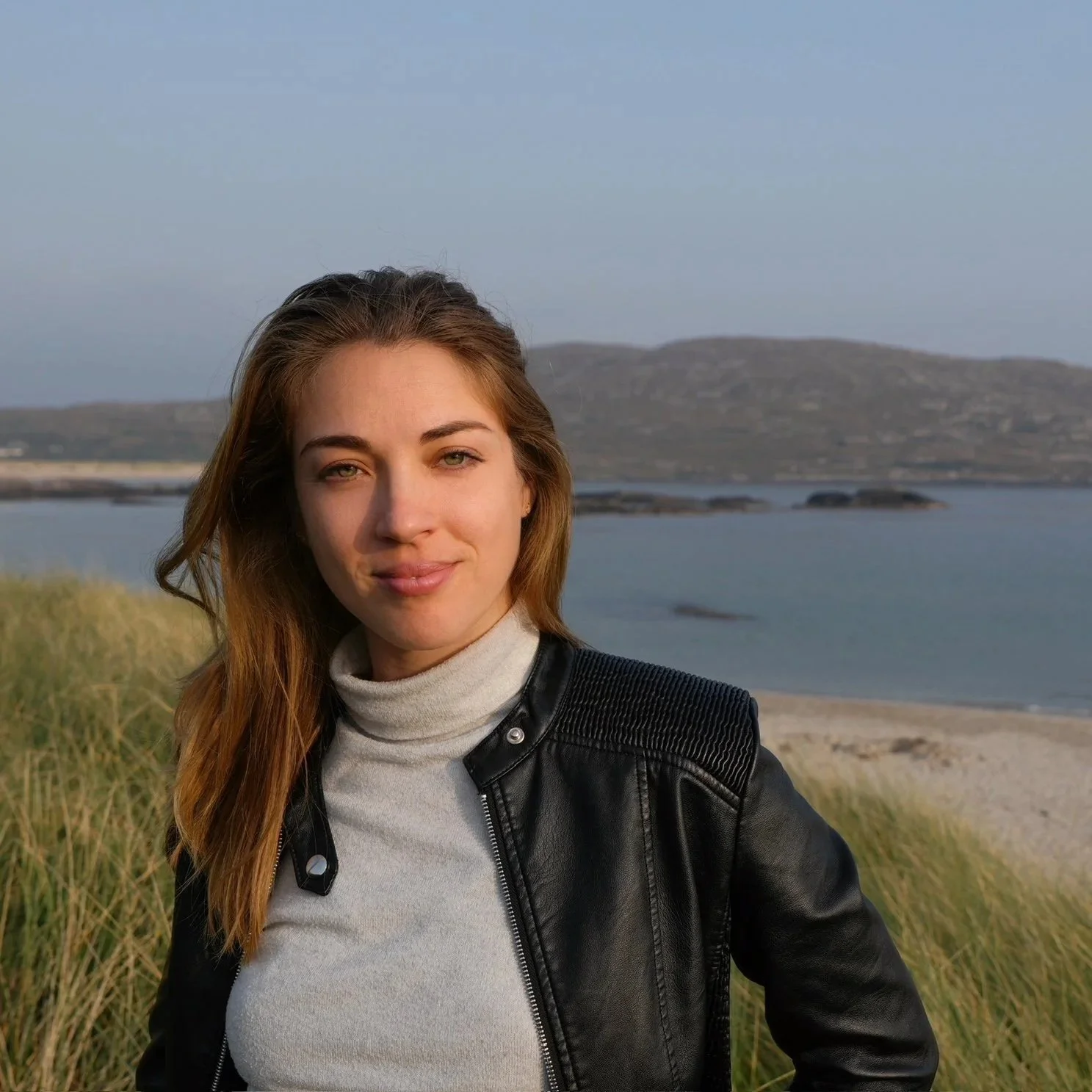 Patricia Machin Portfolio Designer and Art Director Young woman with long blonde brown hair standing outdoors near a body of water with hills in the background Miami