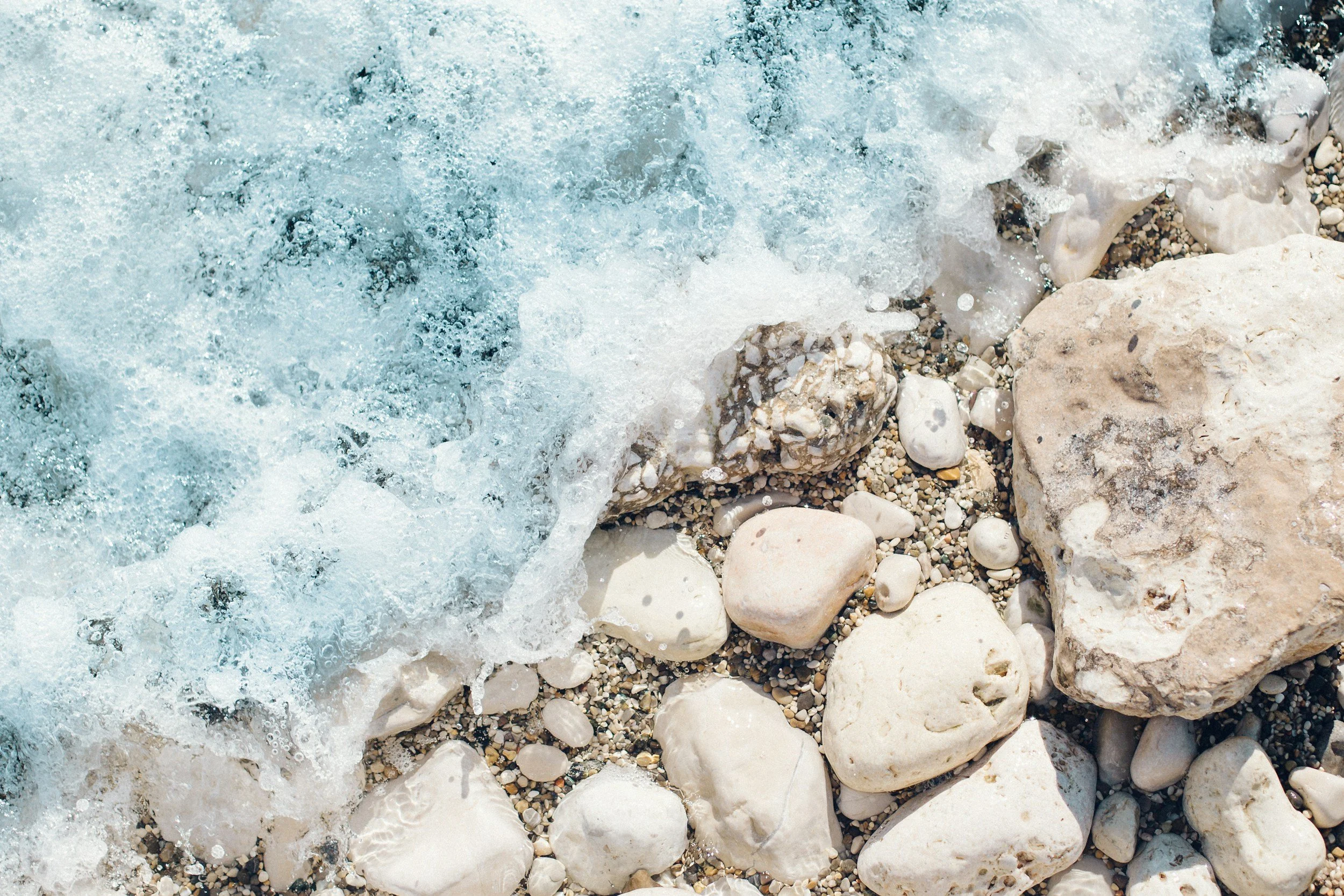 Waves crashing on a rocky shoreline with various-sized white stones