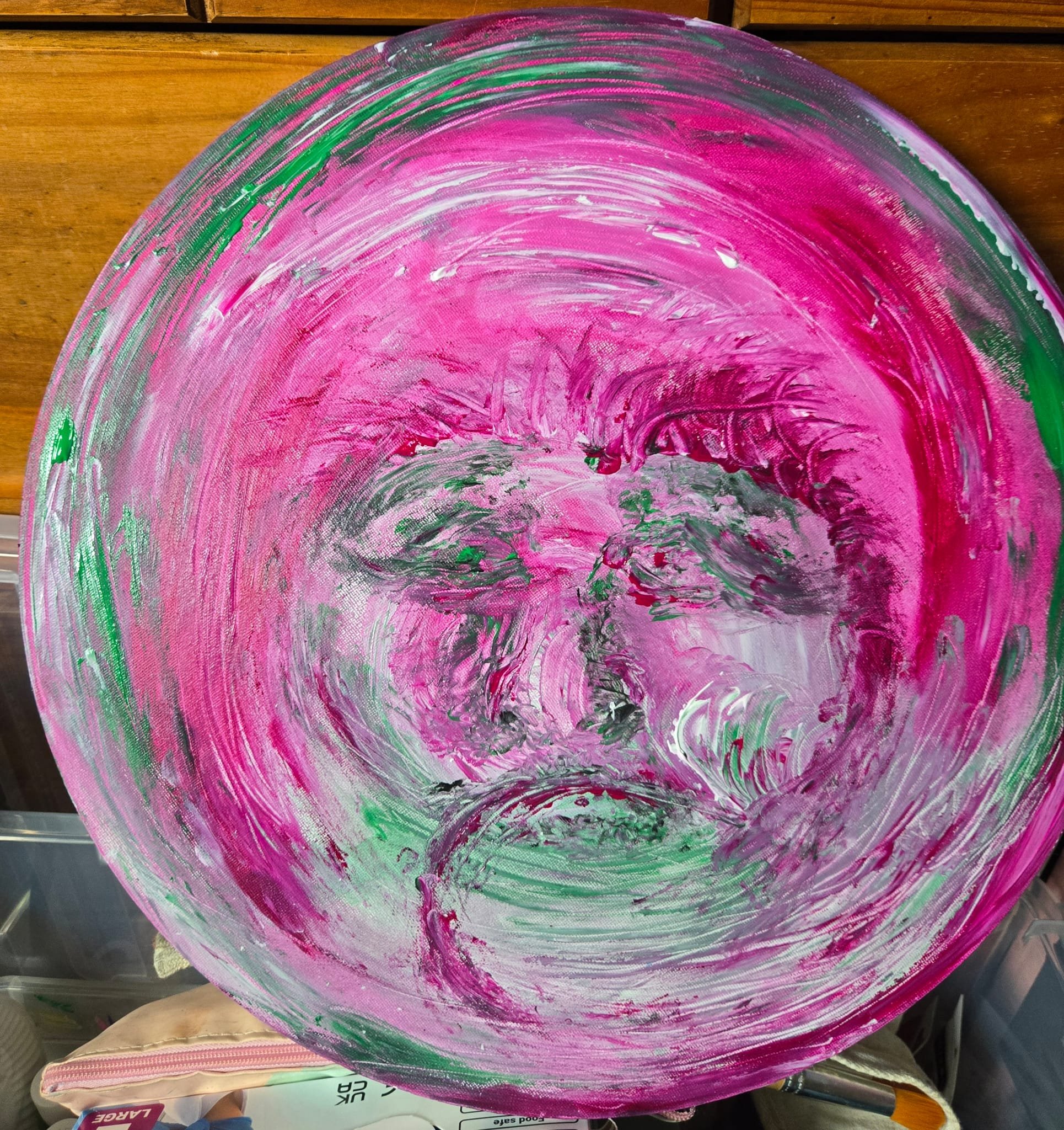 Abstract circular painting with pink, green, gray, and white brushstrokes