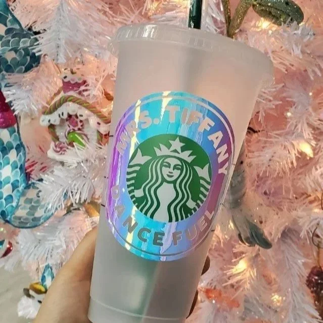 Hand holding a Starbucks plastic tumbler with a holographic design that reads “ Dane Teacher Fuel”.