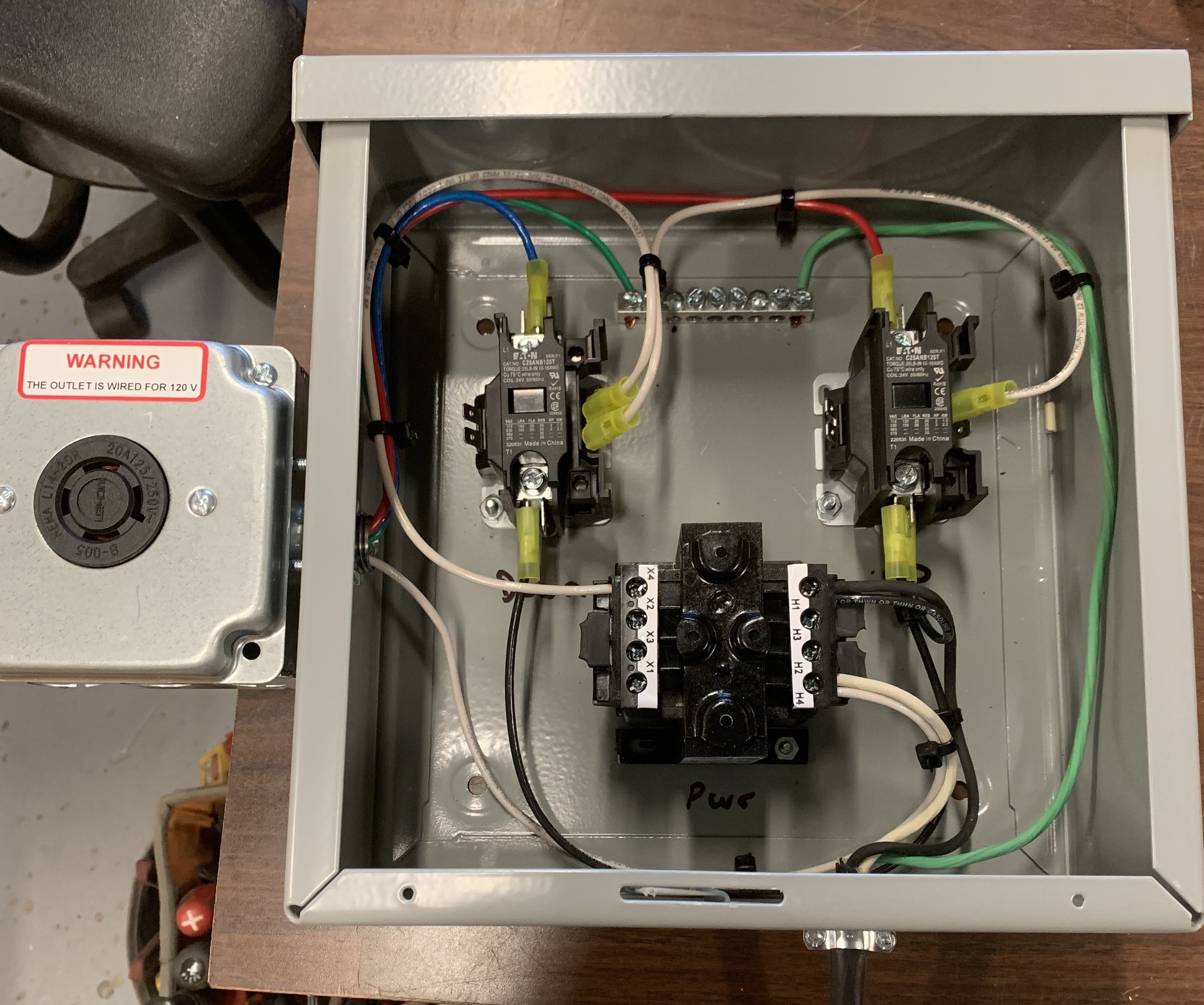 Open electrical box with wired components, including relays, wires, and a power supply labeled for 120V.