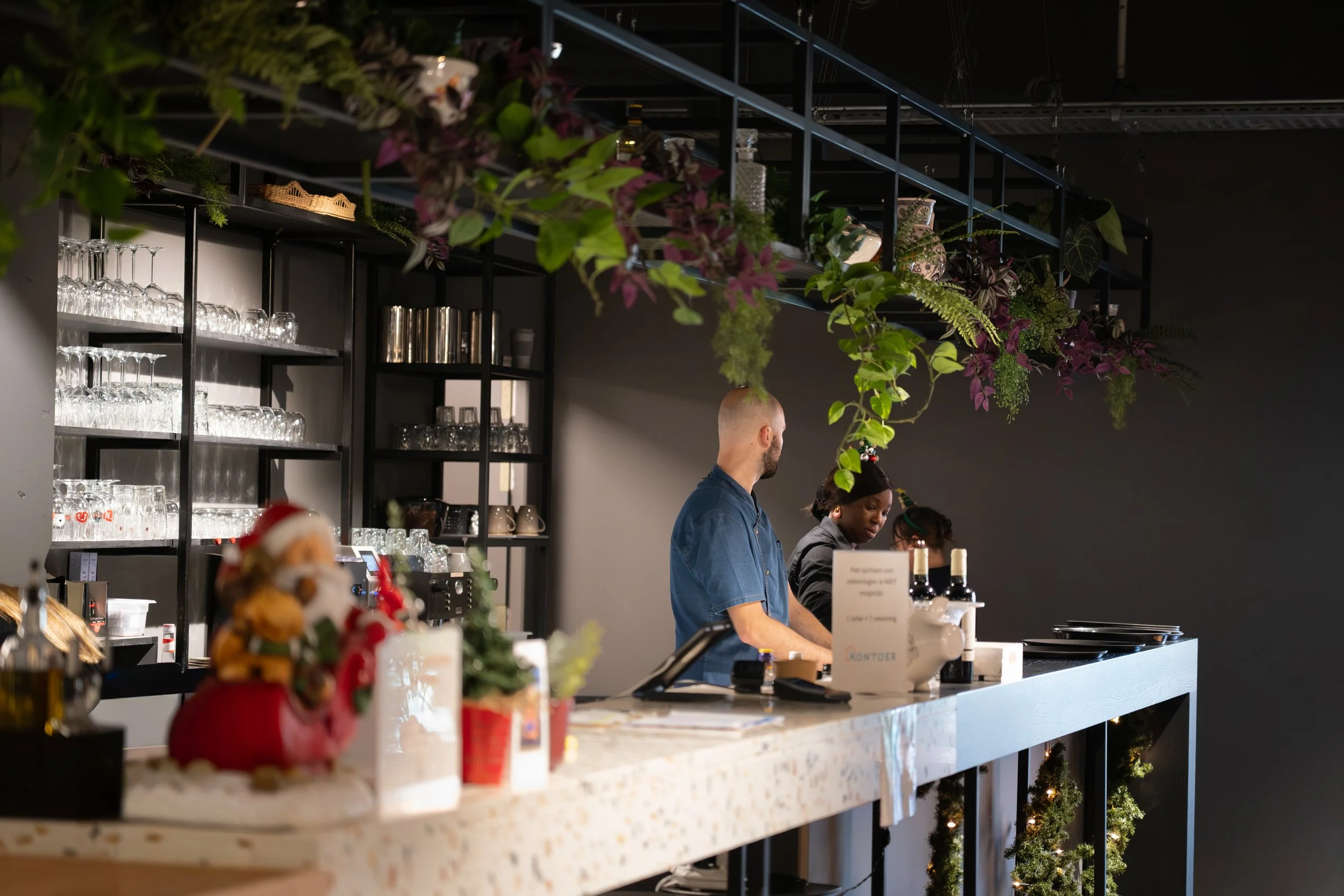 Bartender and staff working behind a decorated bar counter with Christmas decorations and greenery.