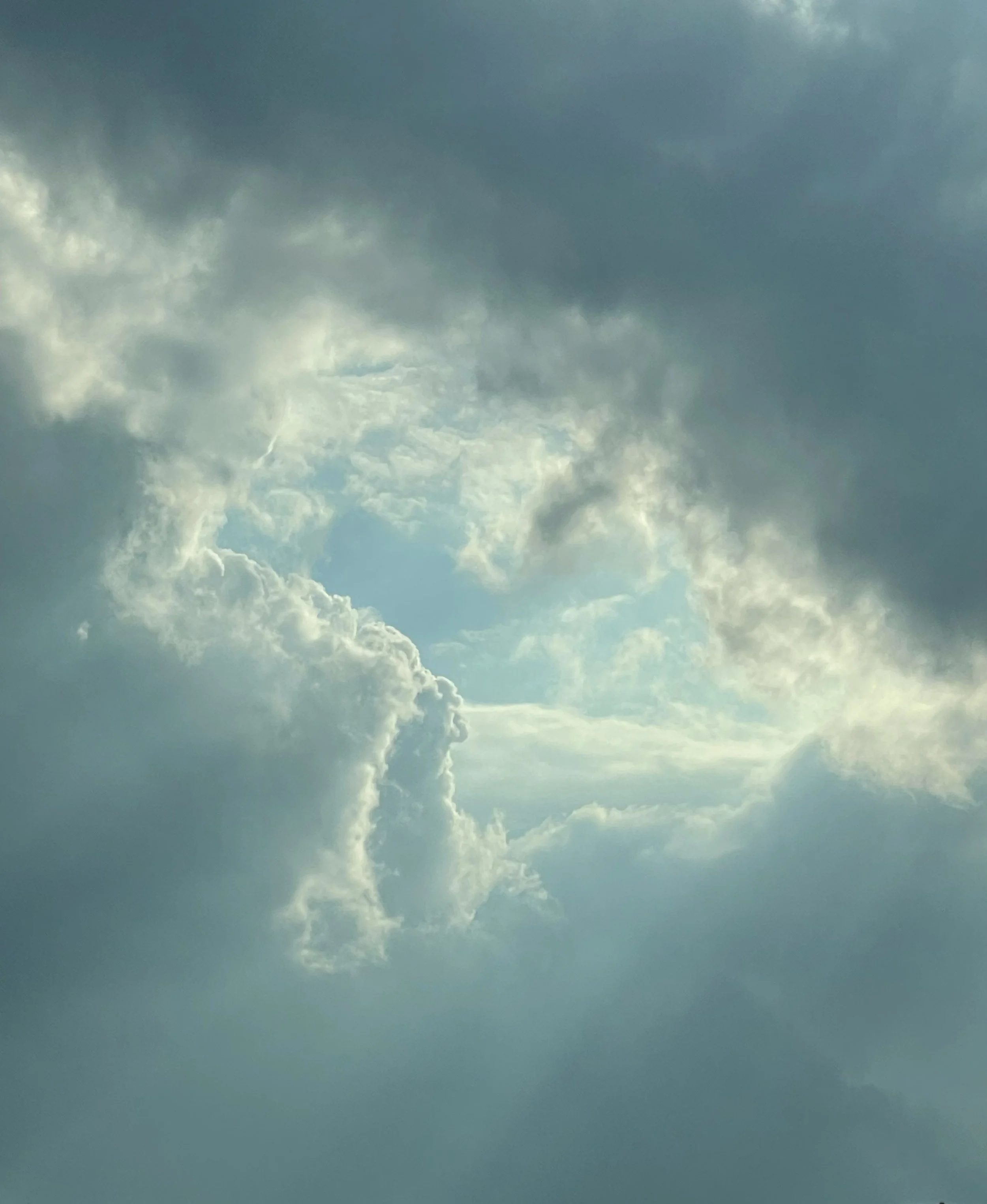 Cloudy sky with a break in the clouds revealing blue sky and sunlight