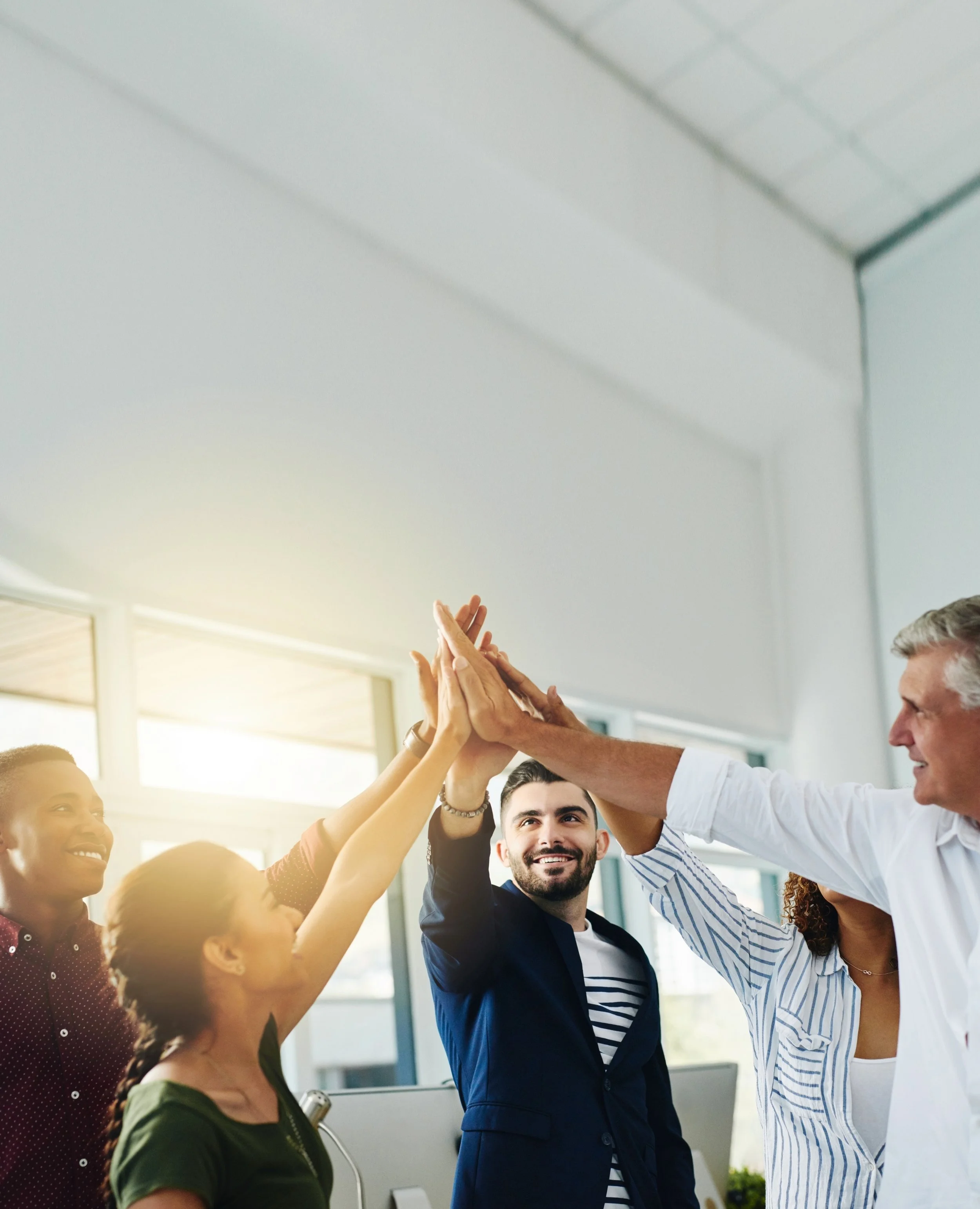 A diverse group of colleagues giving each other high fives in an office.