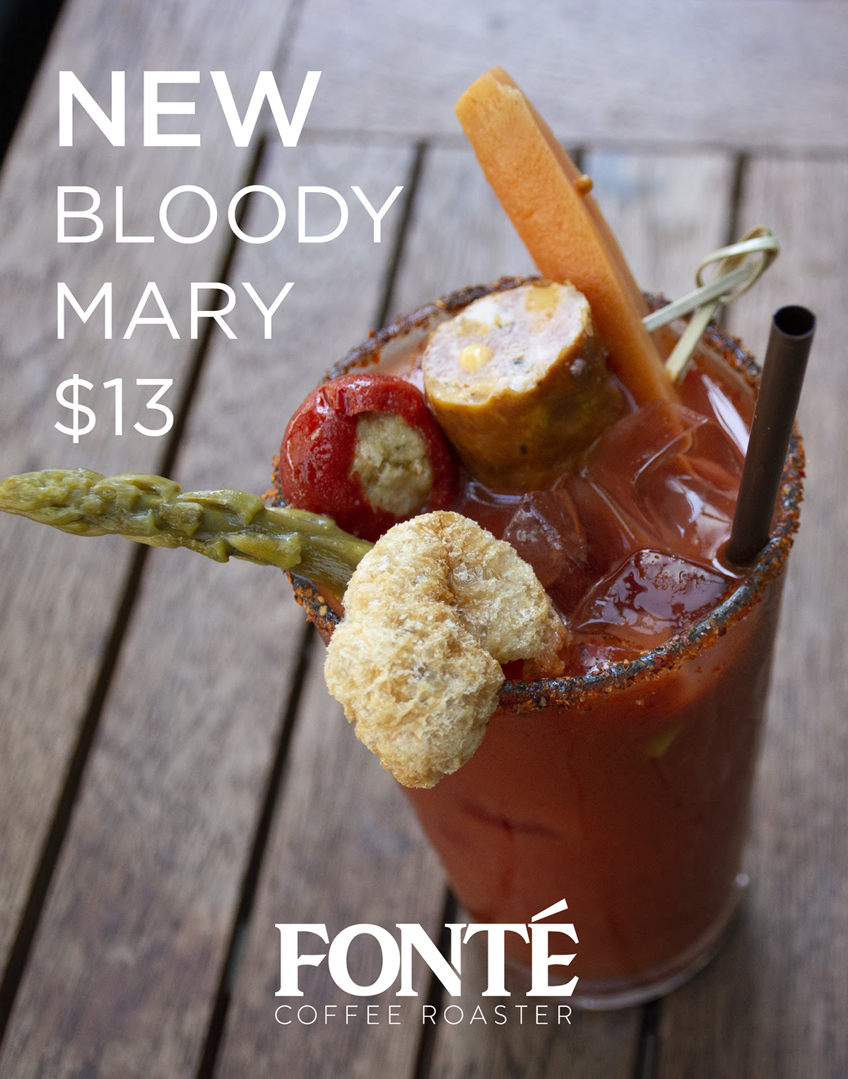 A bloody Mary cocktail garnished with a piece of fried chicken, a cherry tomato, an asparagus spear, a carrot stick, a pickle slice, and a celery stick, in a glass rimmed with chili powder on a wooden surface.