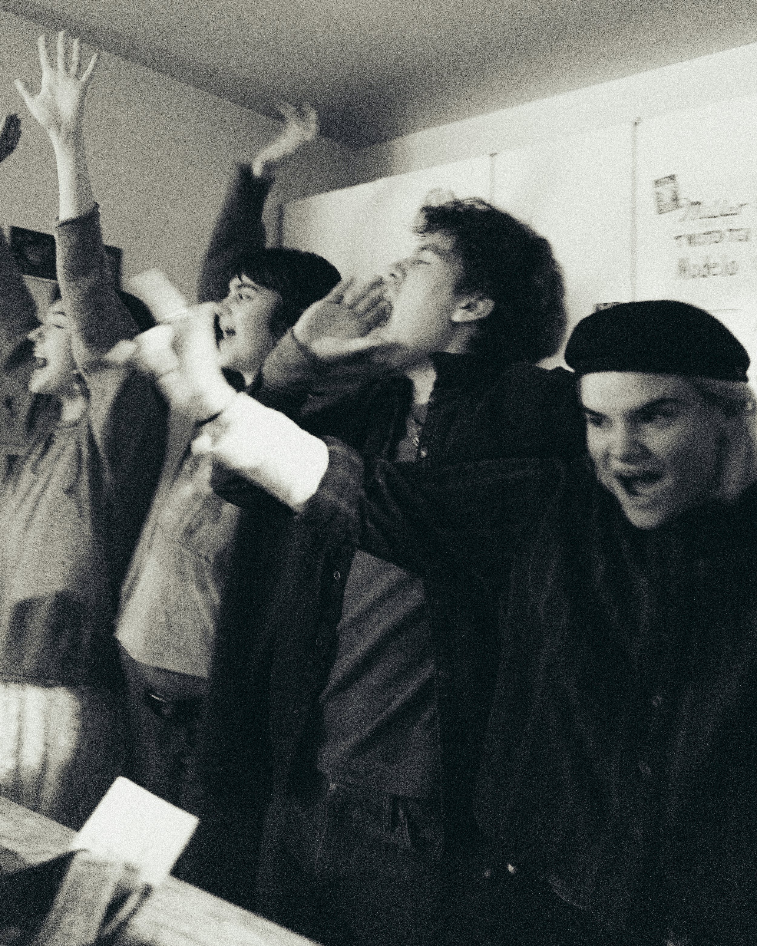 A group of teenagers are singing and dancing in a classroom, expressing joy and excitement.