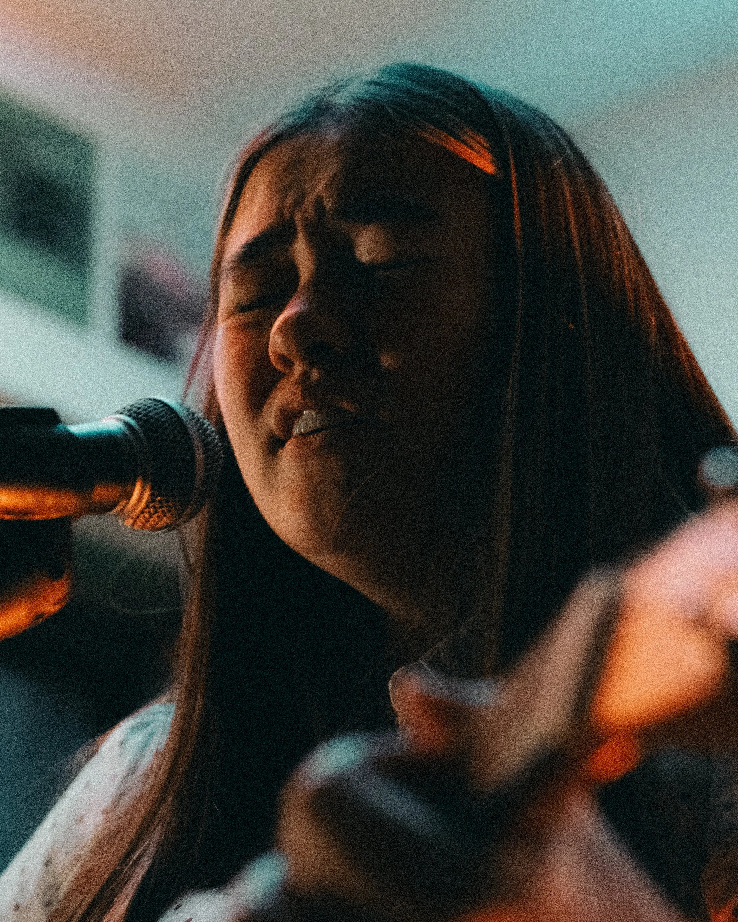 A woman with long hair singing or speaking into a microphone