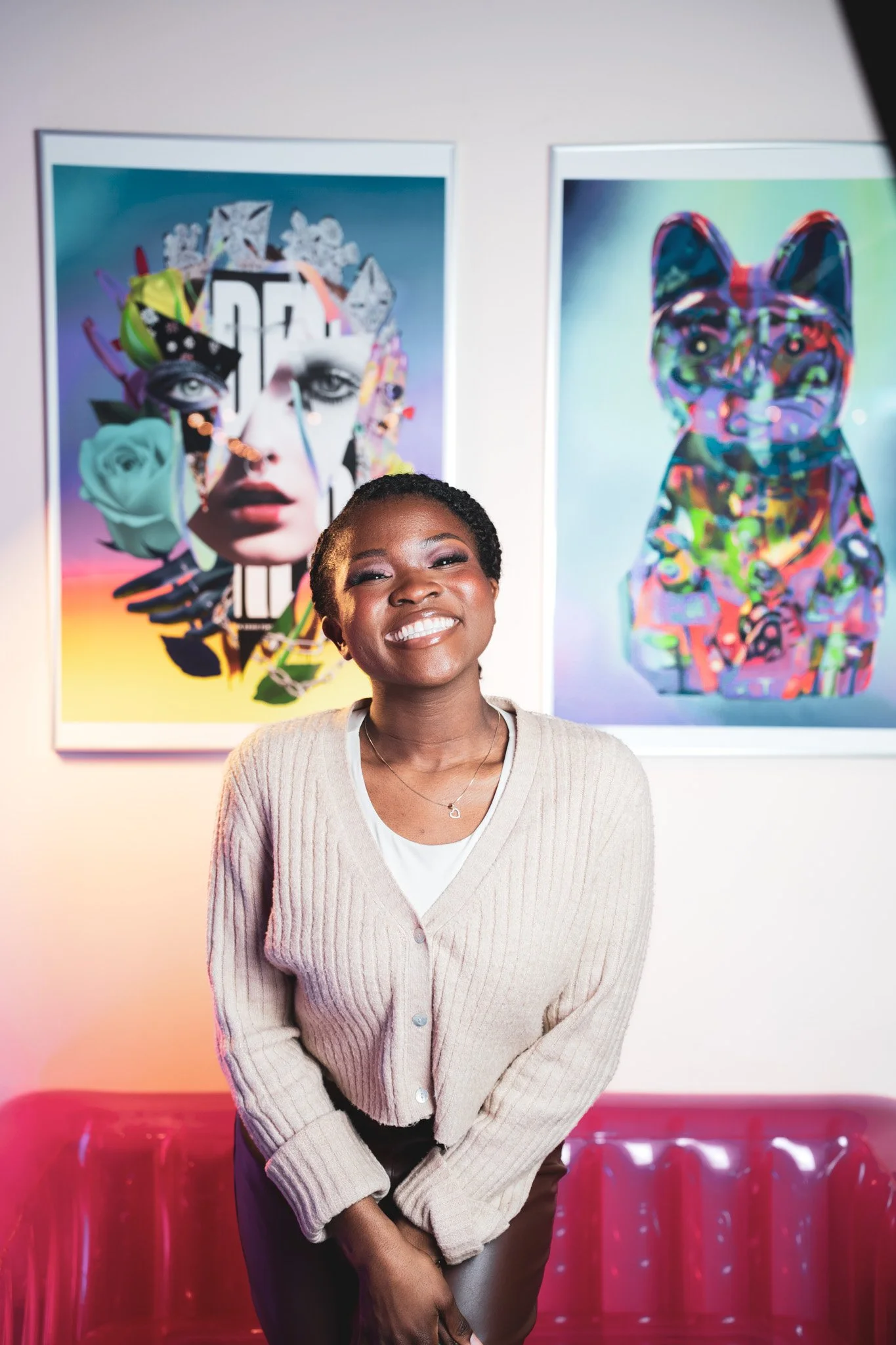 Une femme souriante posant devant deux œuvres d'art modernes dans une galerie ou un musée.