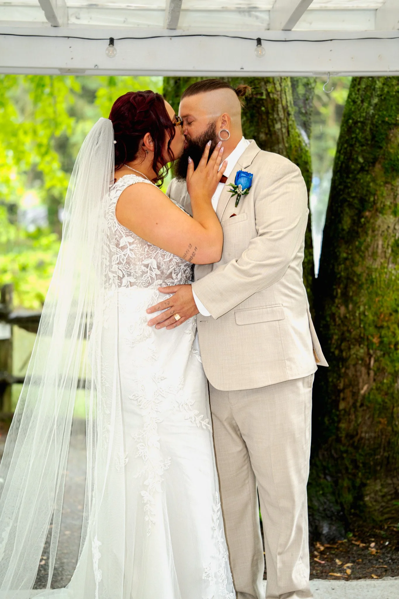 Un couple en robe de mariage et costume s'embrassant lors de leur mariage en plein air.
