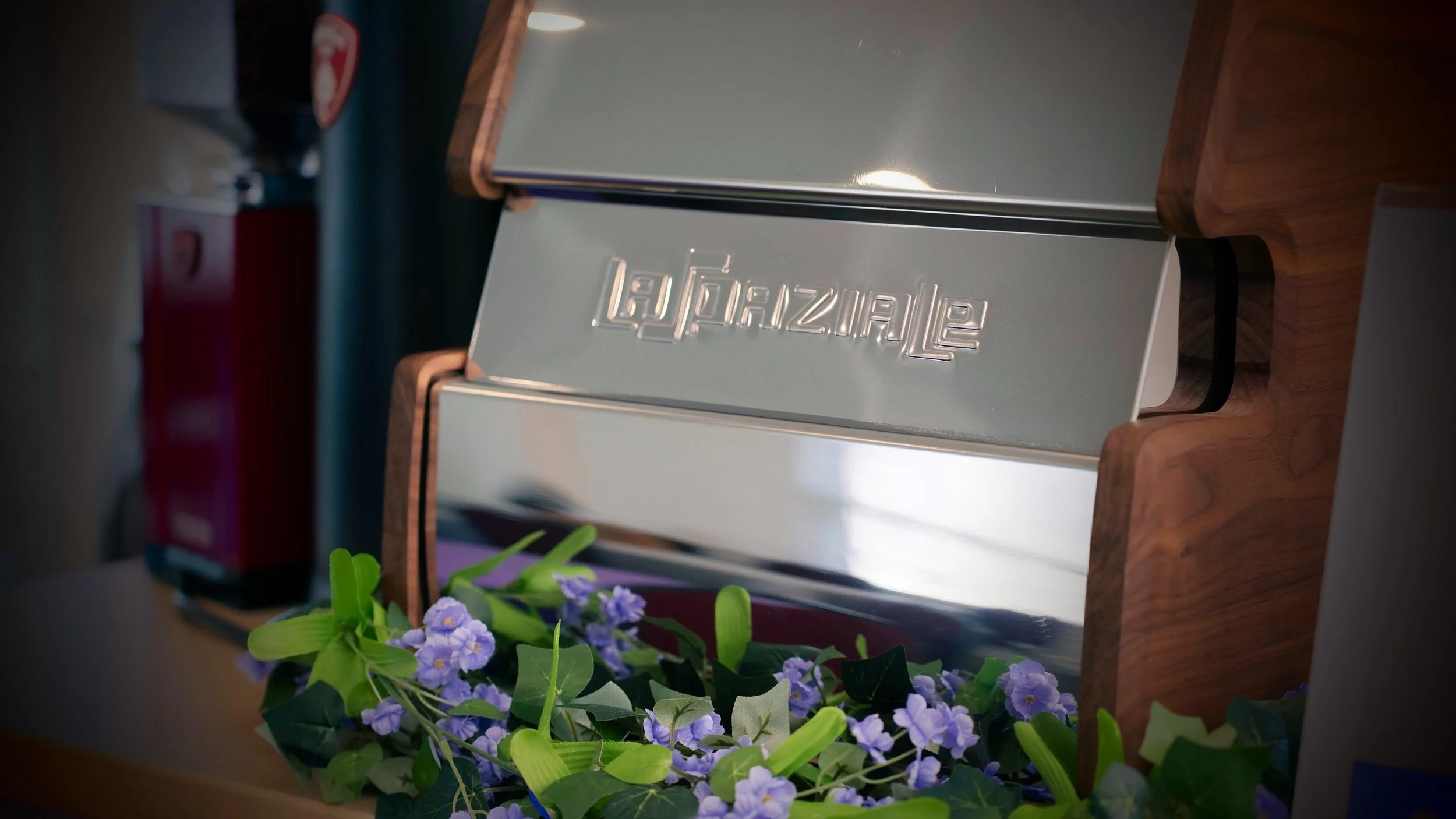 Front of mobile espresso bar decorated with lavender flowers, green leaves, and espresso machine with walnut panels.