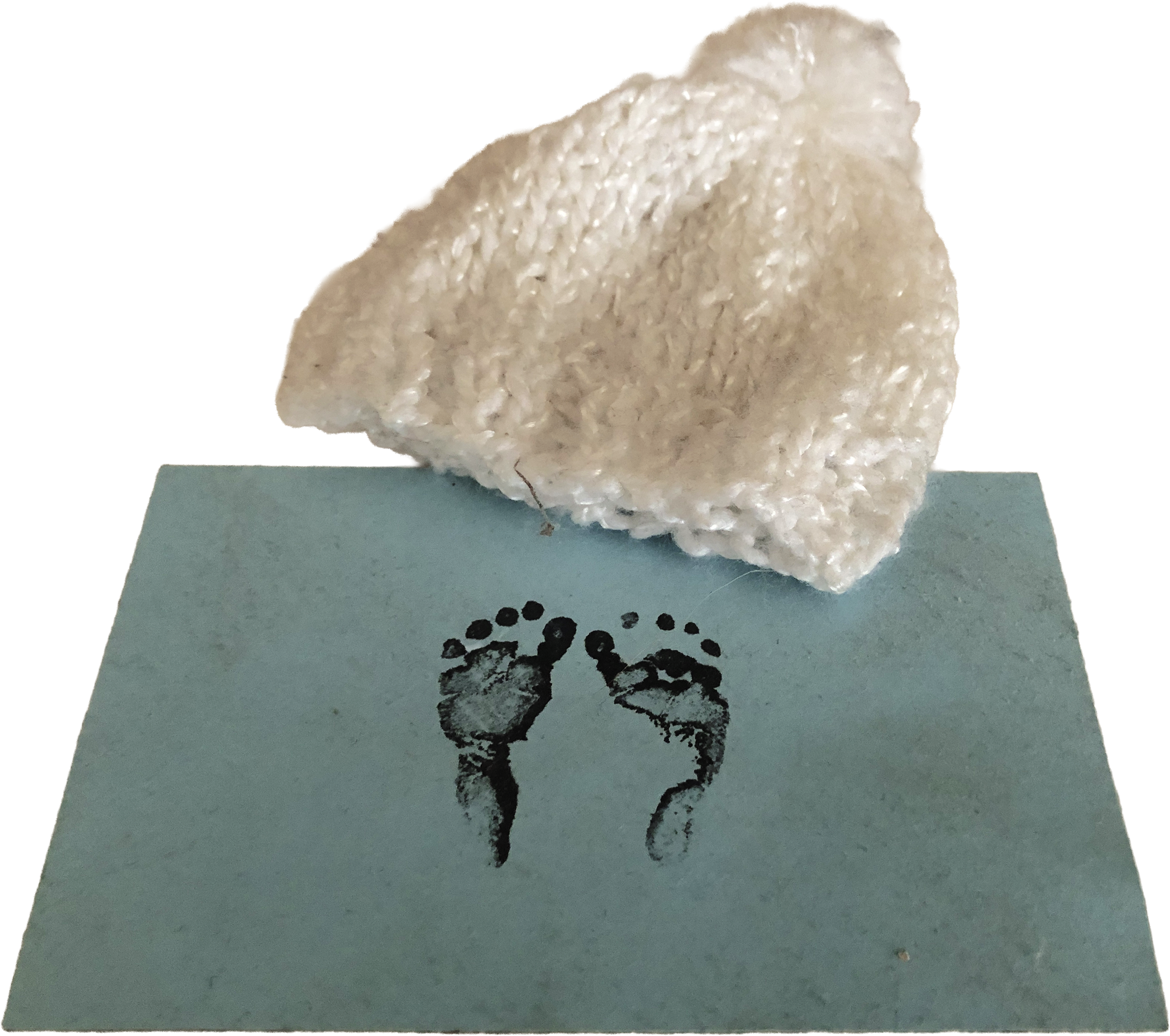 A baby's knit cap and a blue card with baby footprints in ink.